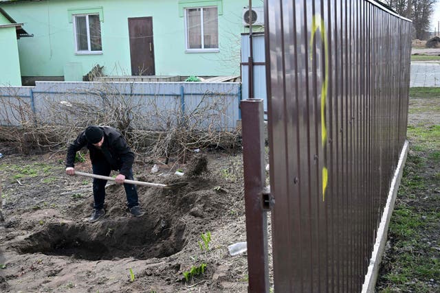 <p>A man exhumes the body of a civilian killed in Andriivka, a village near Kyiv</p>