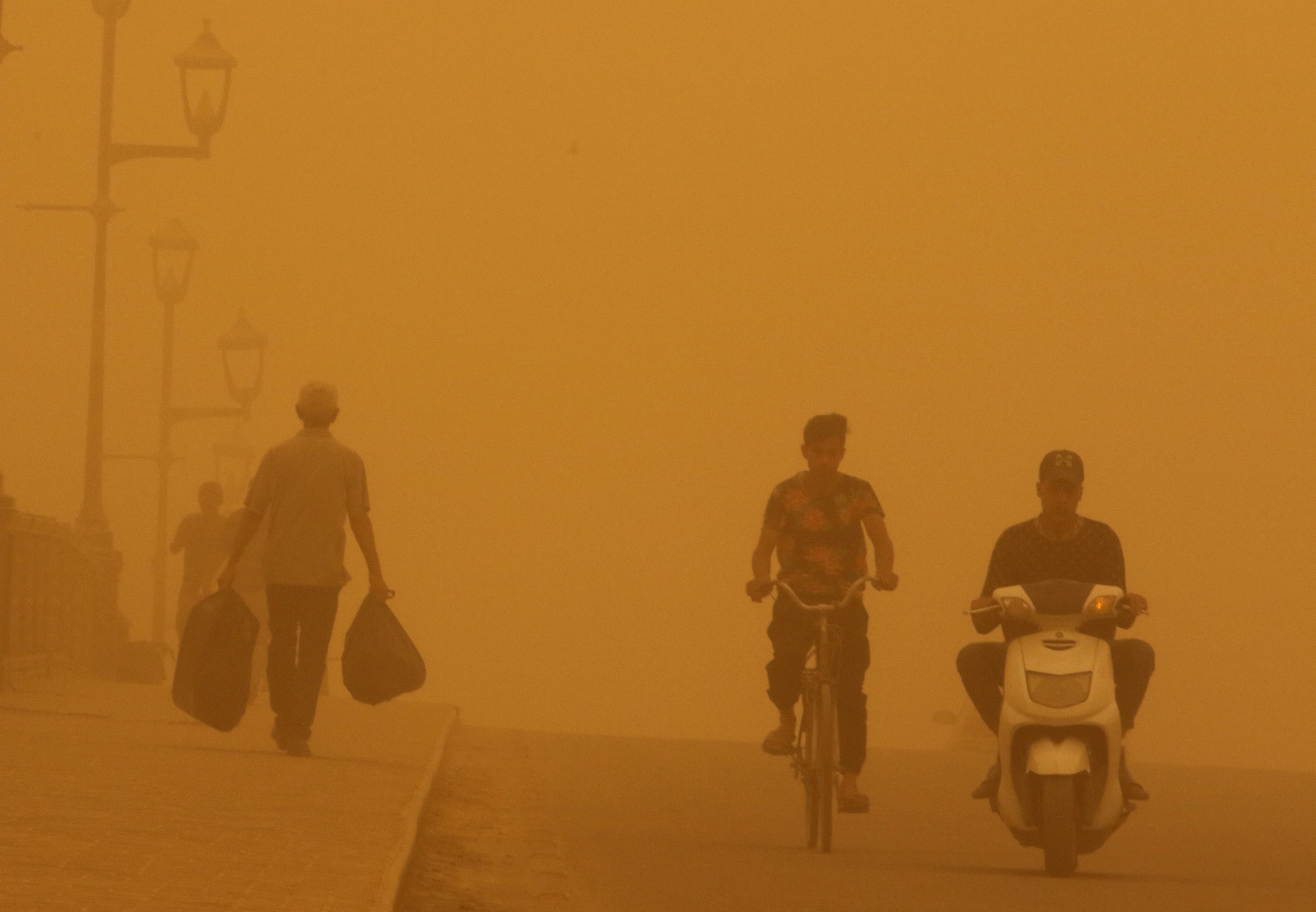 People cross a bridge during a sandstorm in Baghdad on 16 May 2022