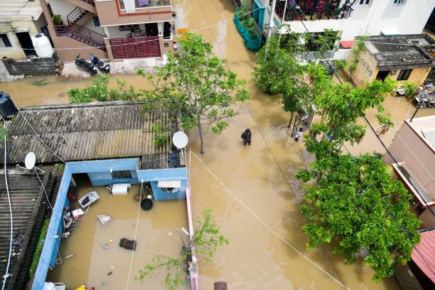 People wade through a flooded street in Bengaluru on 18 May