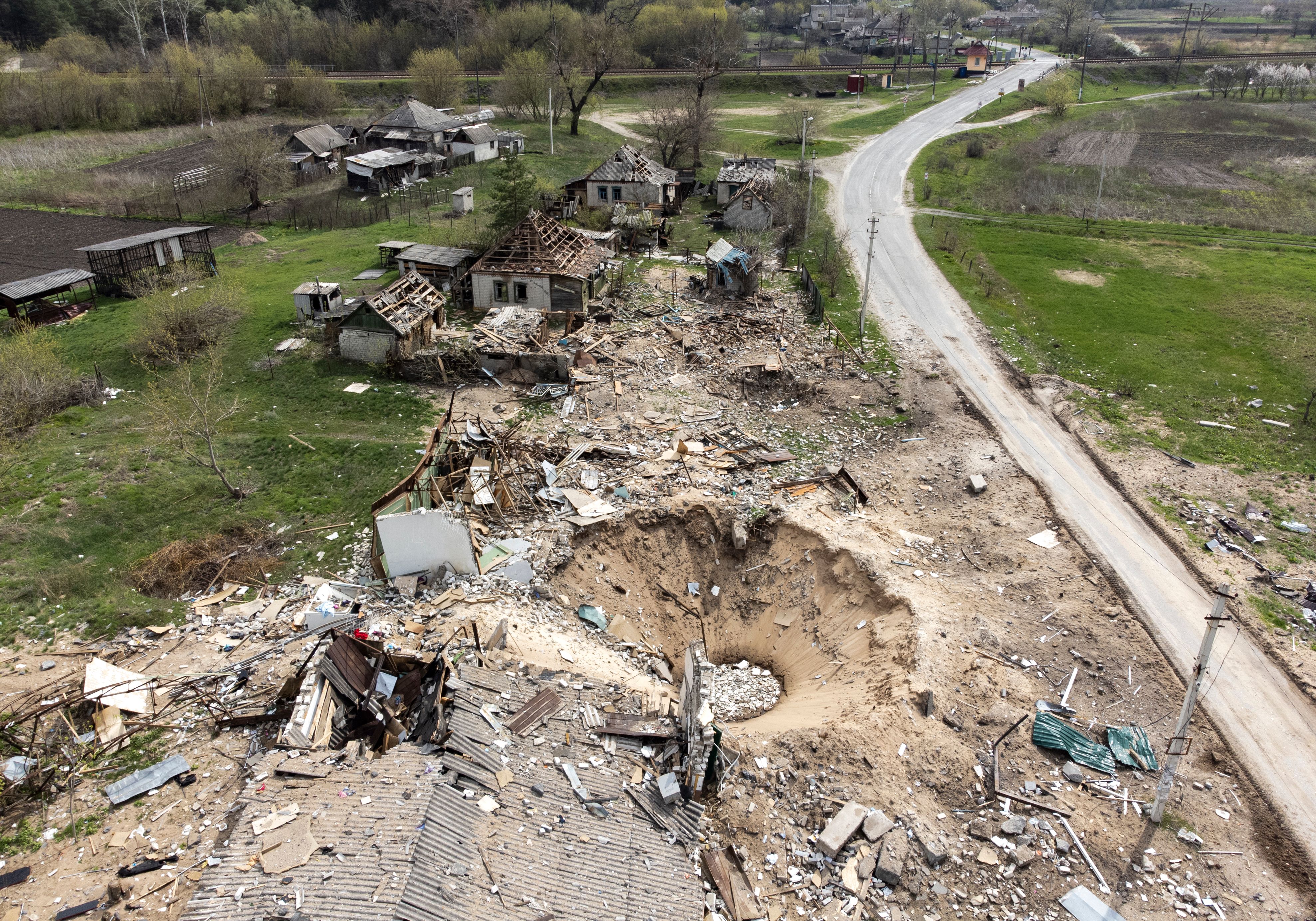 An aerial view shows a crater and destroyed homes in the village of Yatskivka, eastern Ukraine