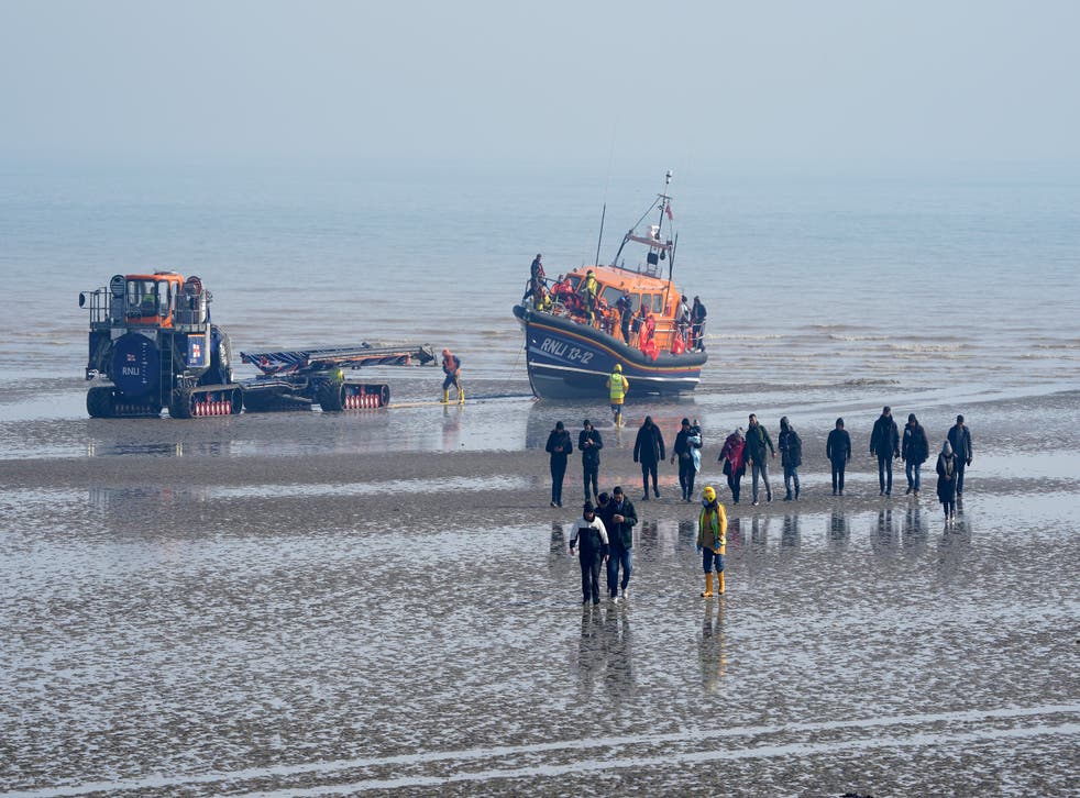 A group of people thought to be migrants are guided up the beach after being brought in to Dungeness, Kent (GaretH Fuller/PA)