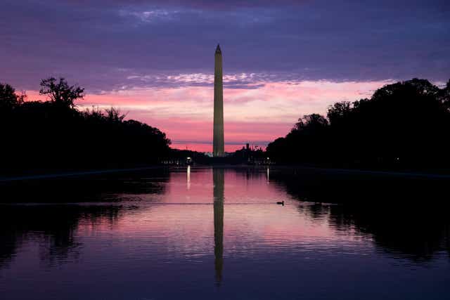 <p>People look at the sun rising at the Lincoln Memorial Reflecting Pool in Washington, DC</p>