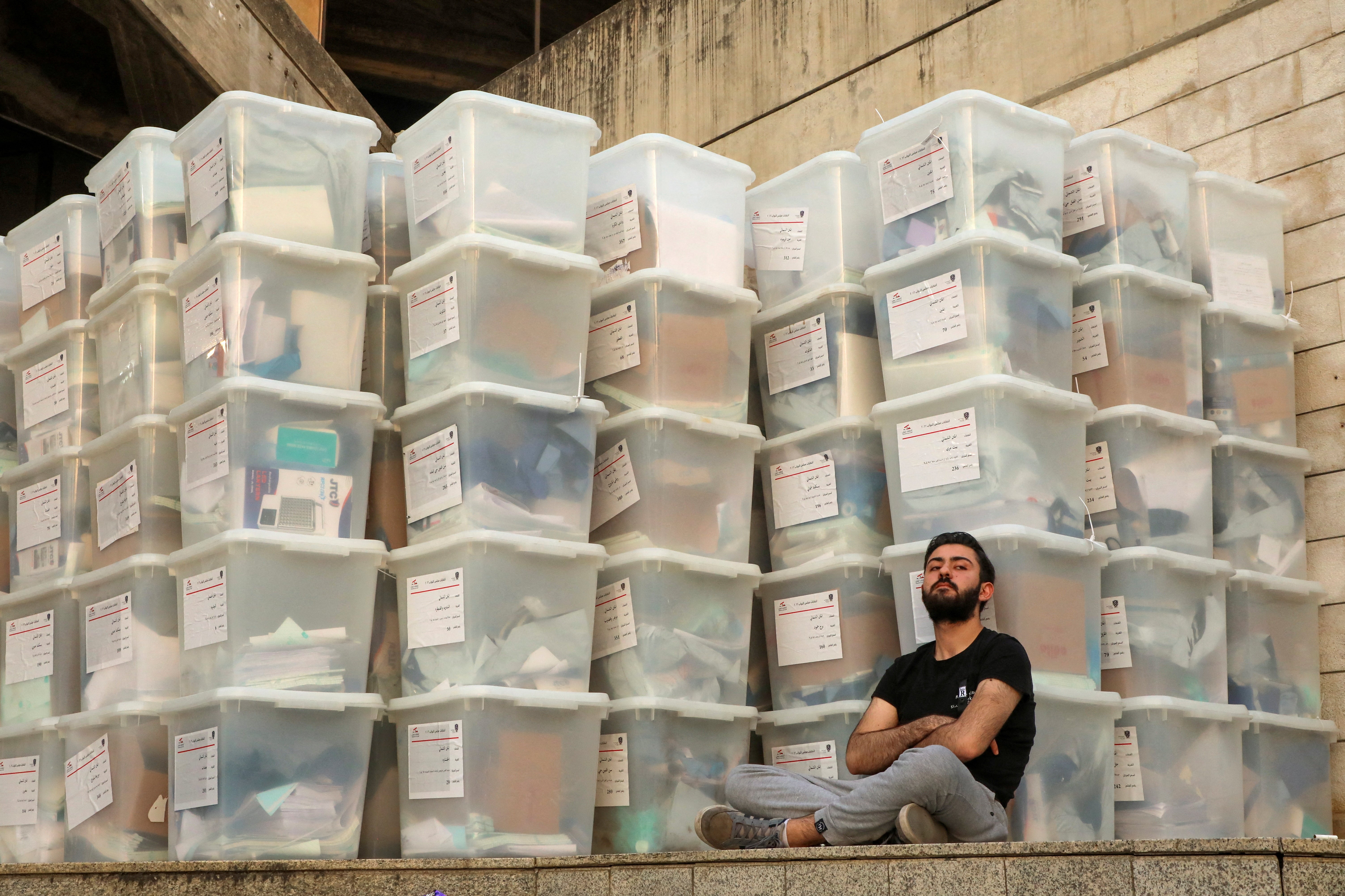 An electoral worker sits next to boxes as Lebanon awaits the official election results