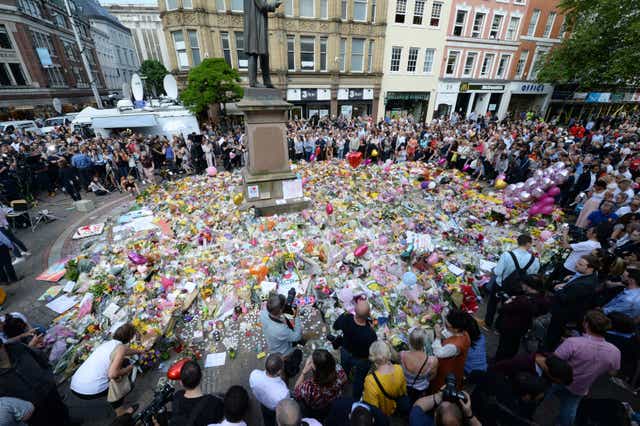 Crowds look at the floral tributes after a minute’s silence in St Ann’s Square, Manchester, to remember the victims of the terror attack in 2017 (Ben Birchall/PA)