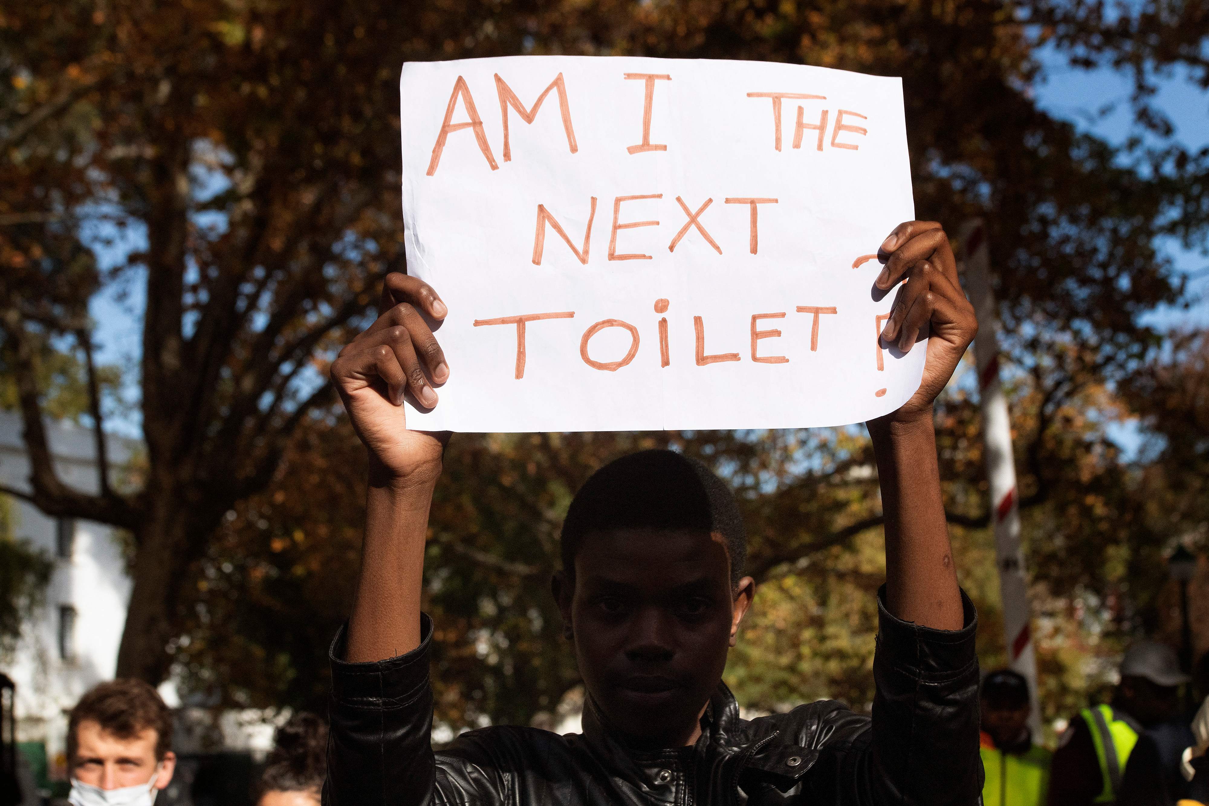 A student holds up a poster saying ‘Am I the next toilet?’ at a student protest against racism at the University of Stellenbosch