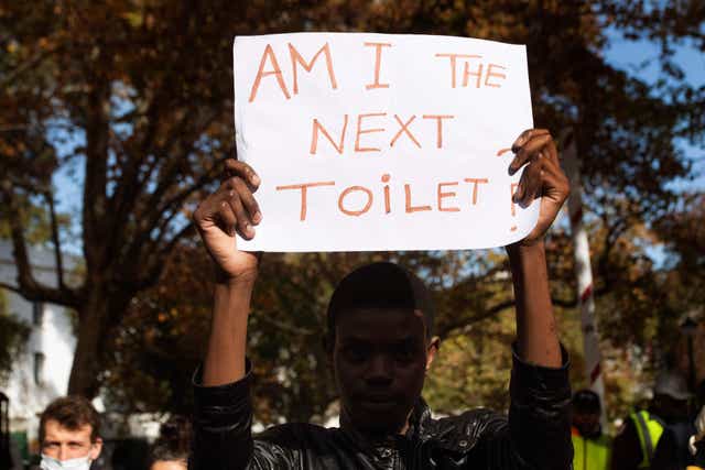 <p>A student holds up a poster saying ‘Am I the next toilet?’ at a student protest against racism at the University of Stellenbosch</p>