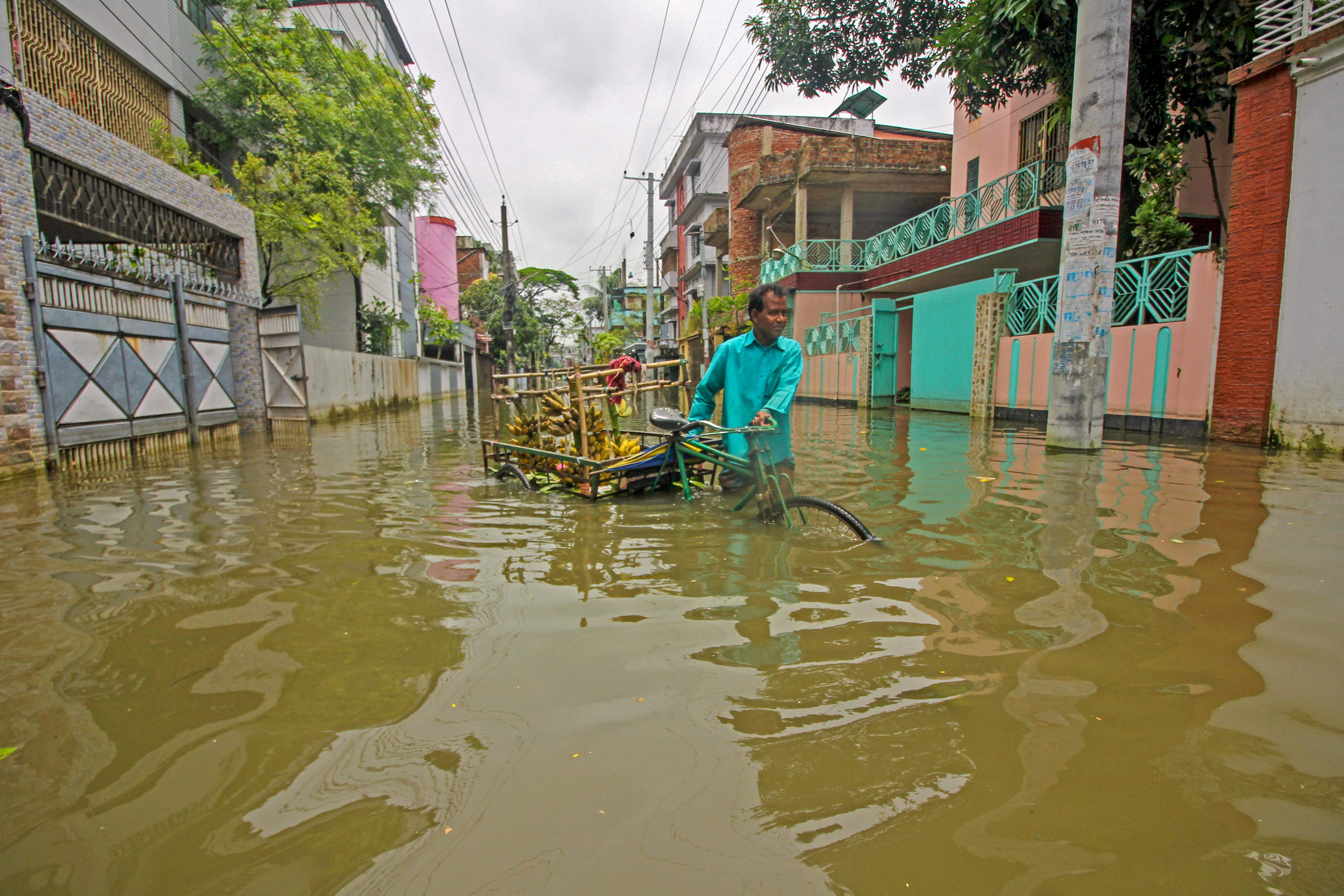 A fruit vendor sells bananas along a flooded street following heavy rains in Sylhet on Saturday