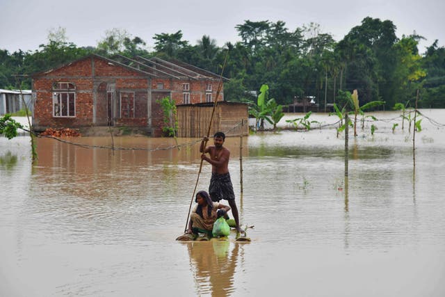 <p>Villagers make their way on a raft past homes in a flooded area after heavy rains in Nagaon district, Assam state, on Saturday </p>