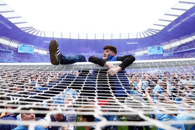 Manchester City fans invade the pitch after their side won the Premier League title (Martin Rickett/PA)