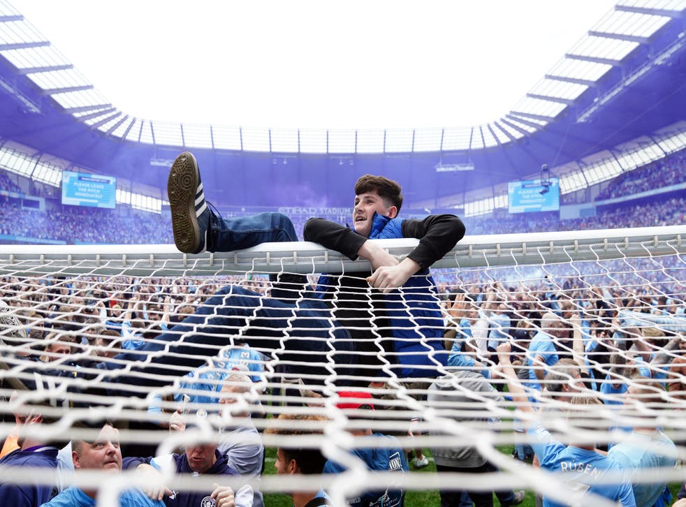 Manchester City fans invade the pitch after their side won the Premier League title (Martin Rickett/PA)