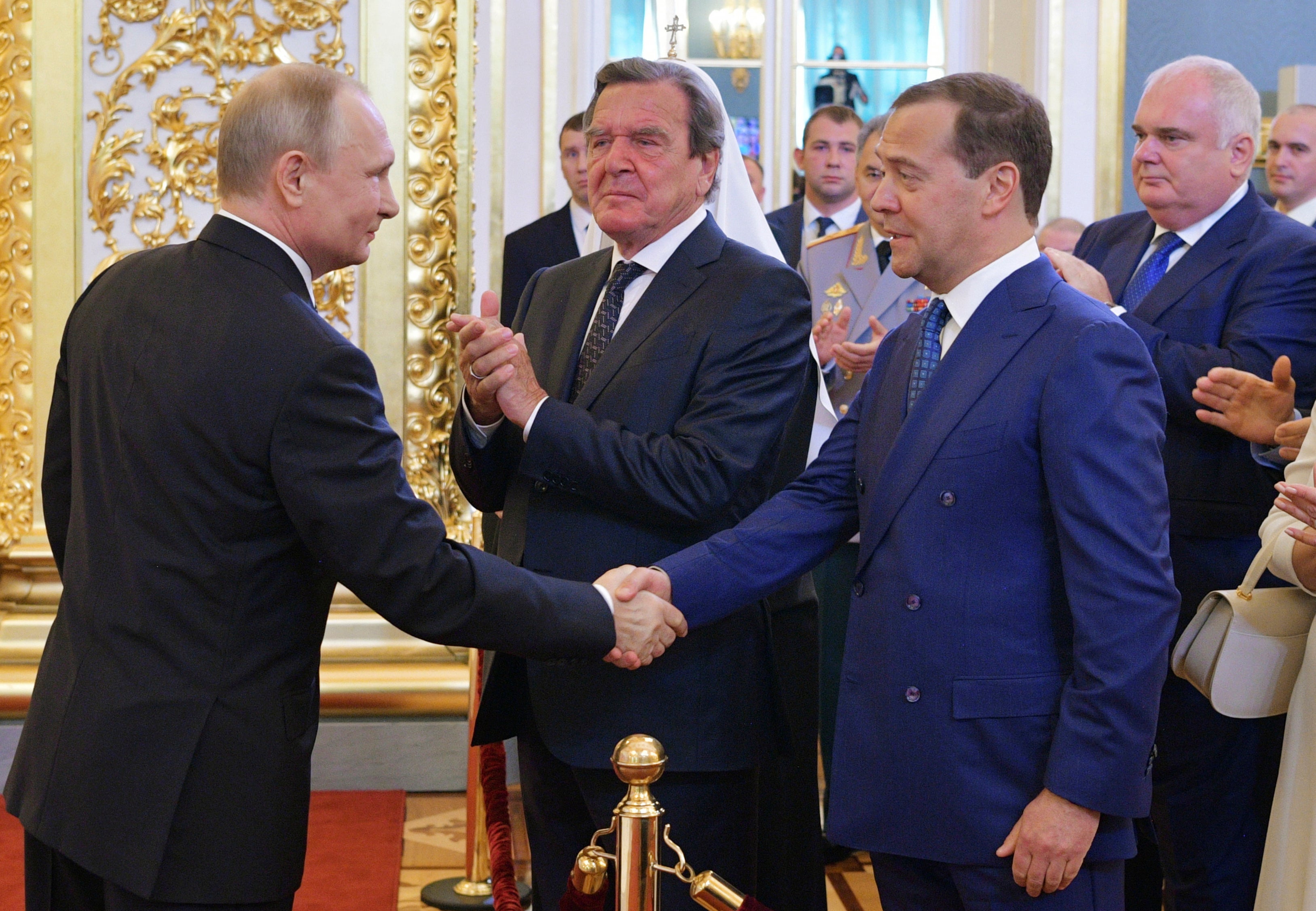 Vladimir Putin [L] shakes the hand of his predecessor Dmitry Medvedev