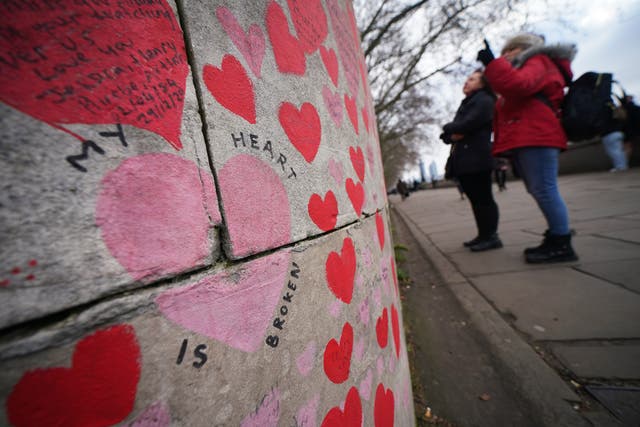 People stop to look at tributes on the Covid memorial wall in central London (Yui Mok/PA)