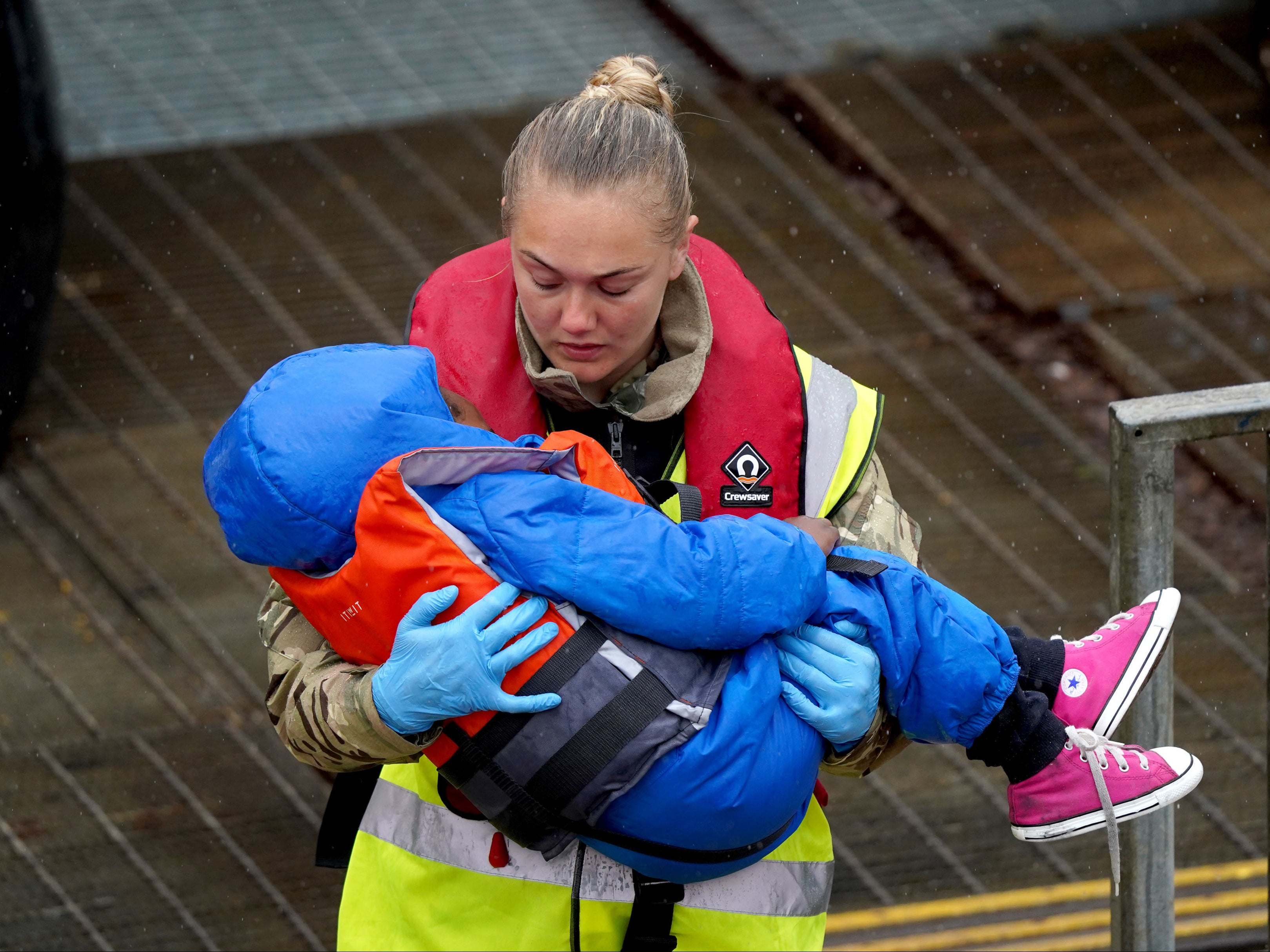 A young child amongst group of people thought to be migrants is carried by a member of the military as they are brought in to Dover, Kent, on 23 May 2022