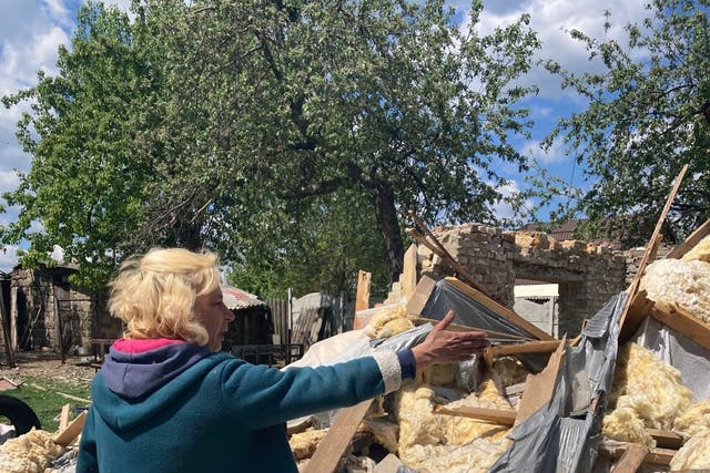 <p>Vasilia Kirilev points to what is left of her home in Vilkhivka near Kharkiv</p>