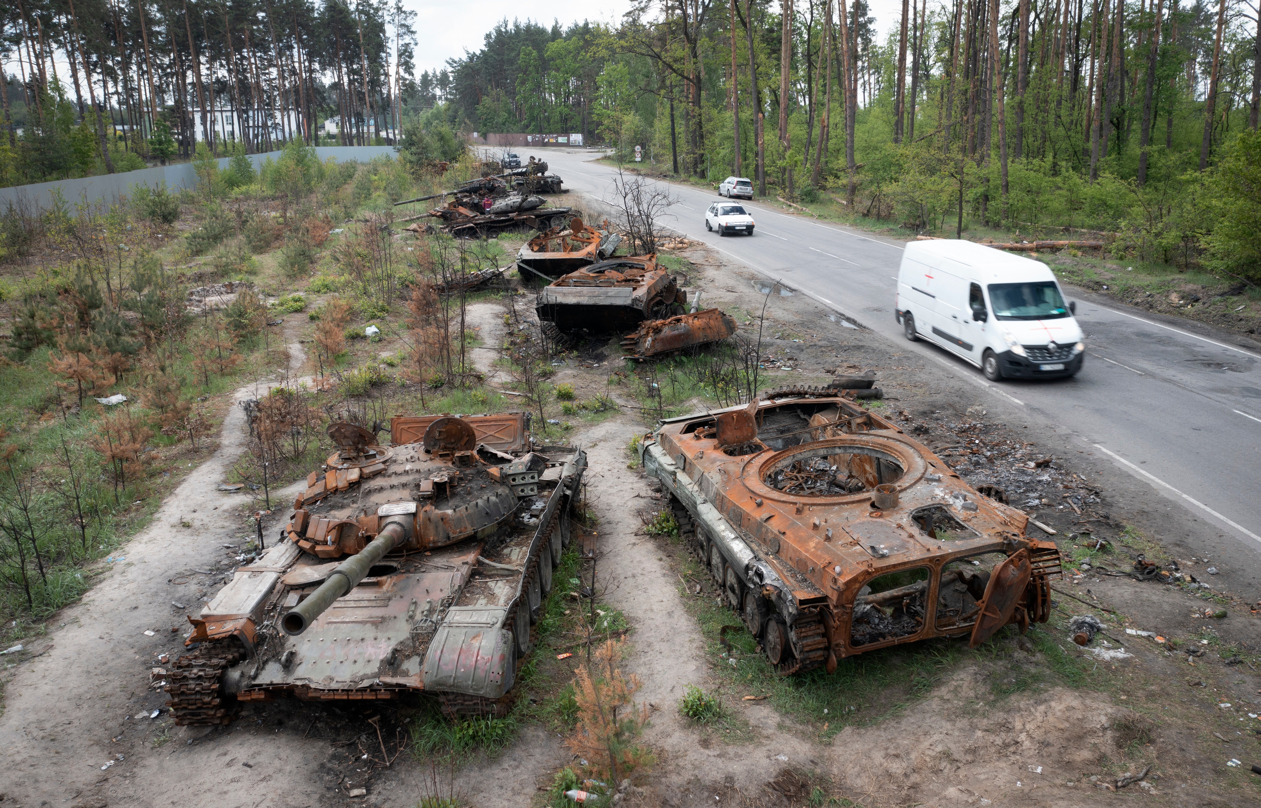 Cars pass by destroyed Russian tanks in a recent battle against Ukrainians in the village of Dmytrivka, close to Kyiv, Ukraine, Monday, May 23, 2022. (AP Photo/Efrem Lukatsky)