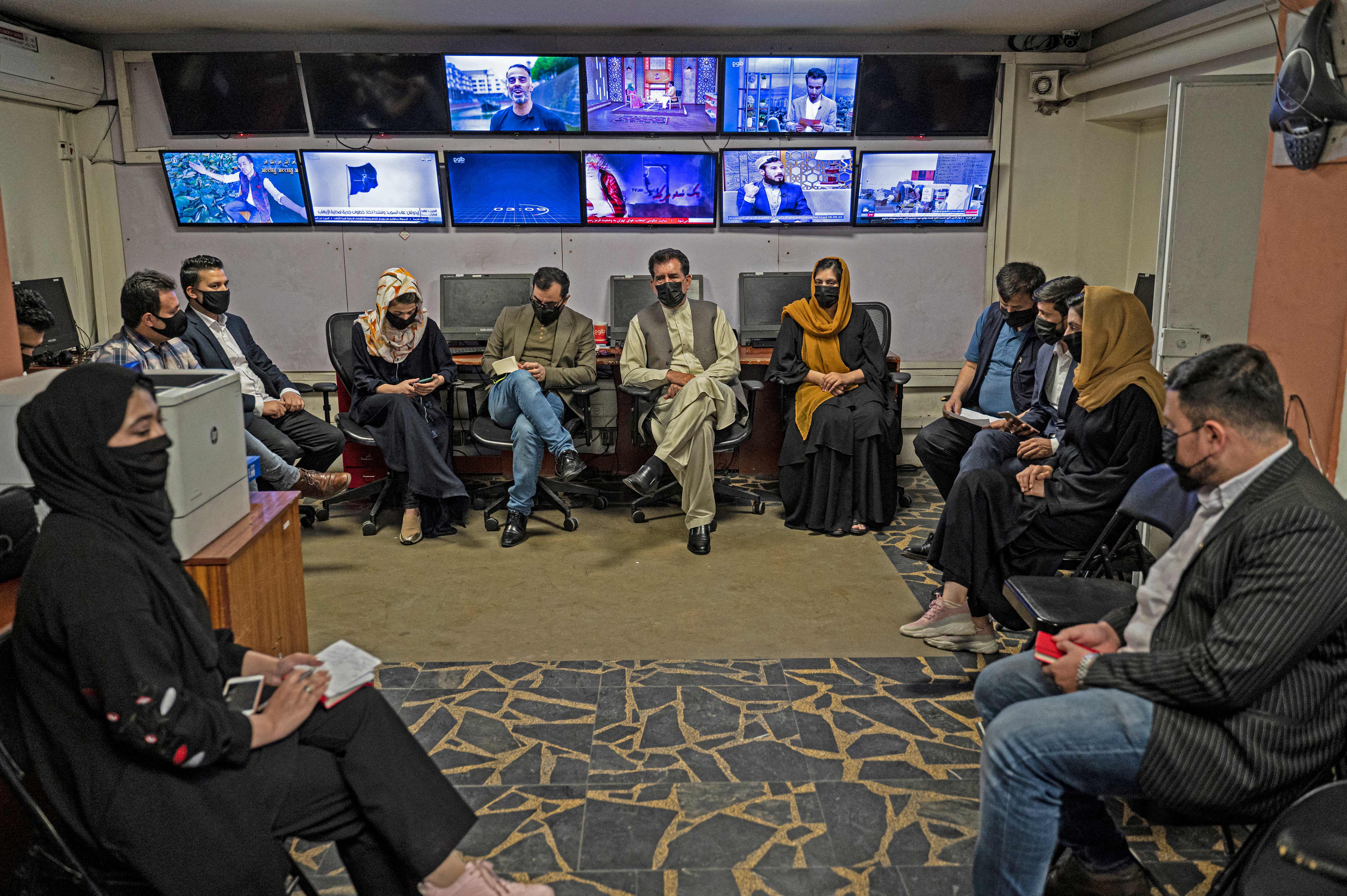 Reporters for Tolo News cover their faces as they attend an editorial meeting at Tolo TV station in Kabul on May 22, 2022.