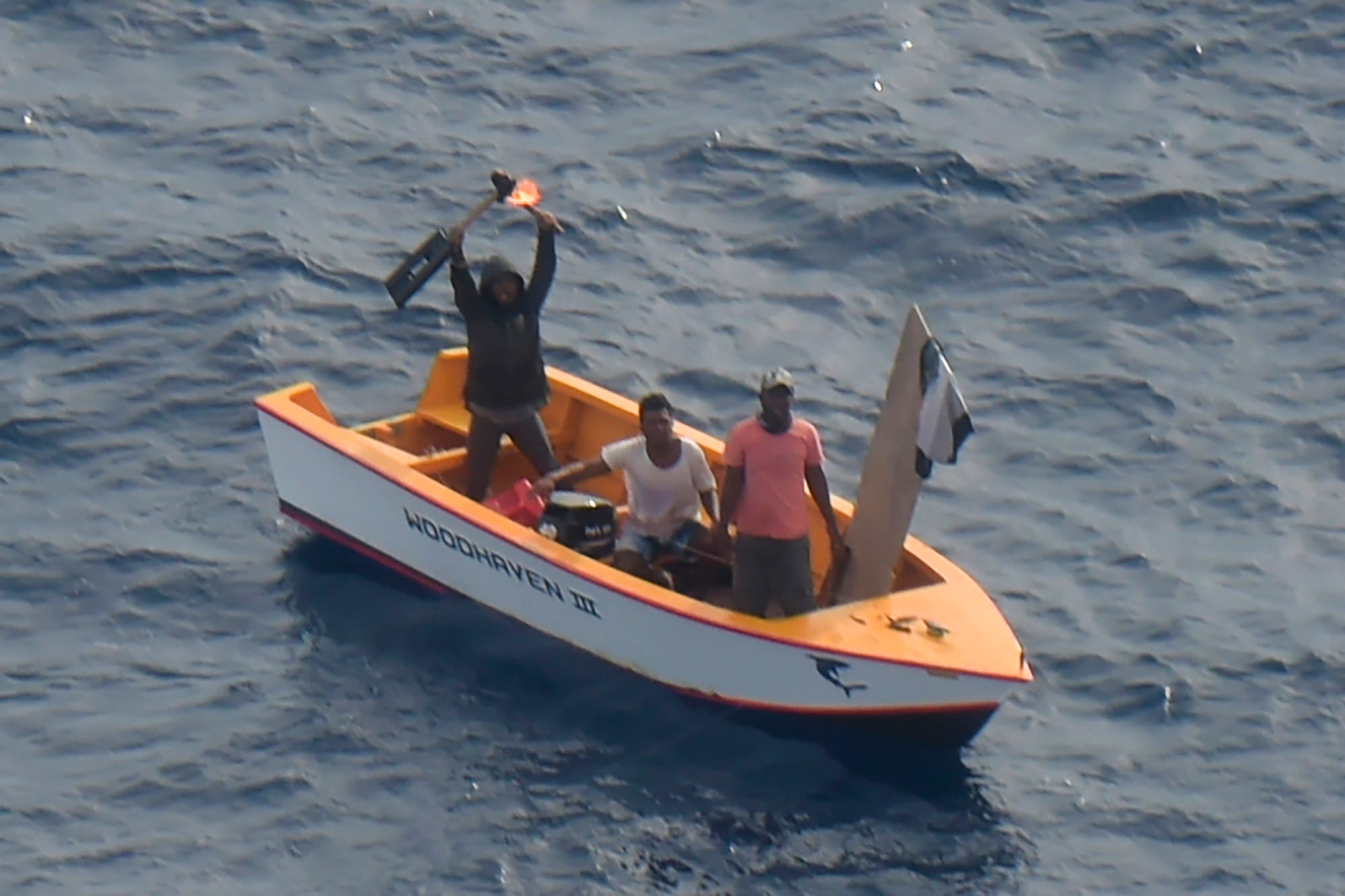 Crew members of one of the rescued boats wave to Royal New Zealand Air Force plane near Makin Island in Kiribati