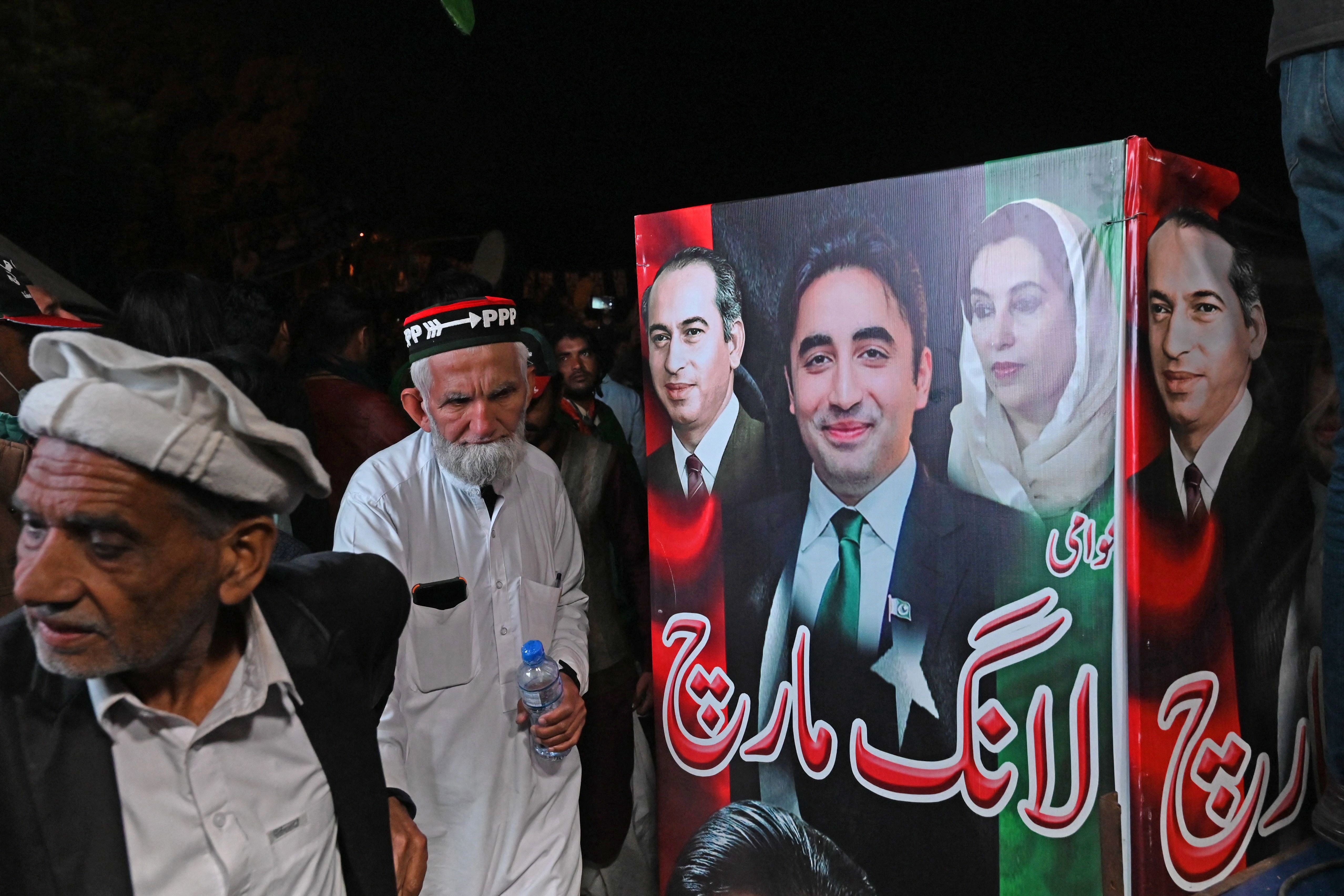 Supporters of Pakistan Peoples Party (PPP) gather around a poster of PPP Chairman Bilawal Bhutto Zardari