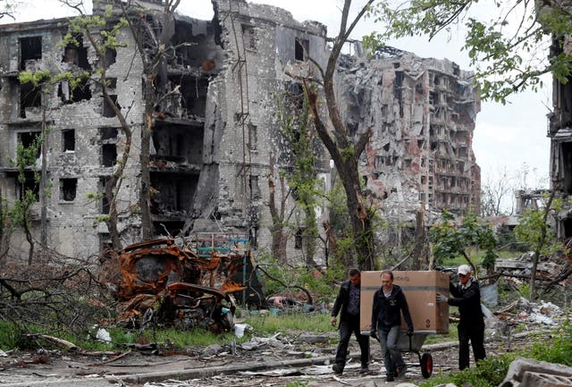 <p>Local residents transport a box on a wheelbarrow past a heavily damaged apartment building near Azovstal Iron and Steel Works, during Ukraine-Russia conflict in the southern port city of Mariupol</p>