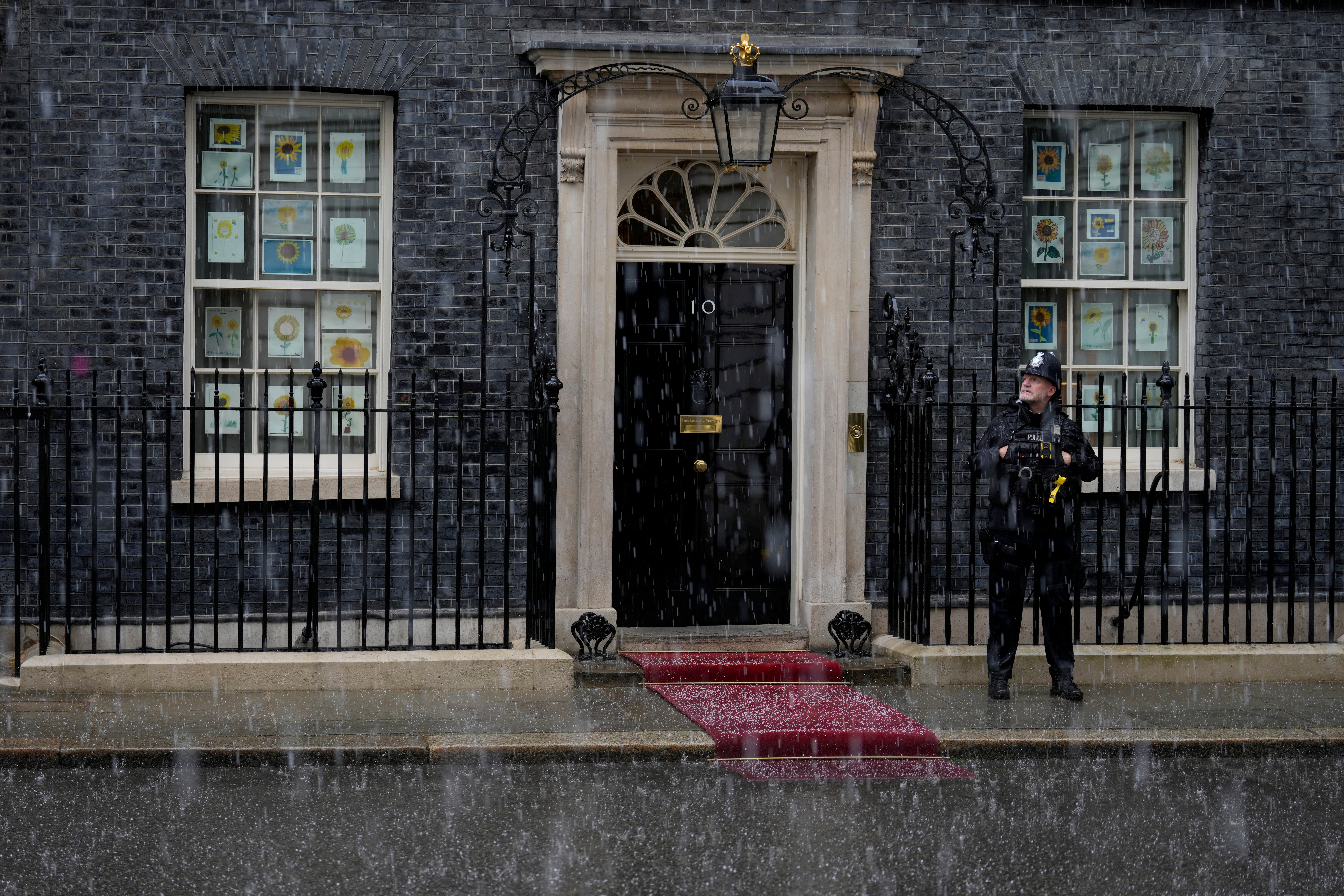 Hail falls during a thunder and lighting storm as a police officer stands guard outside 10 Downing Street in London