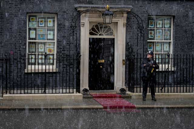 <p>Hail falls during a thunder and lighting storm as a police officer stands guard outside 10 Downing Street in London</p>