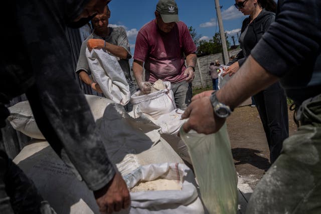 People receive flour at a food donation spot in Kharkiv (Bernat Armangue/AP/PA)