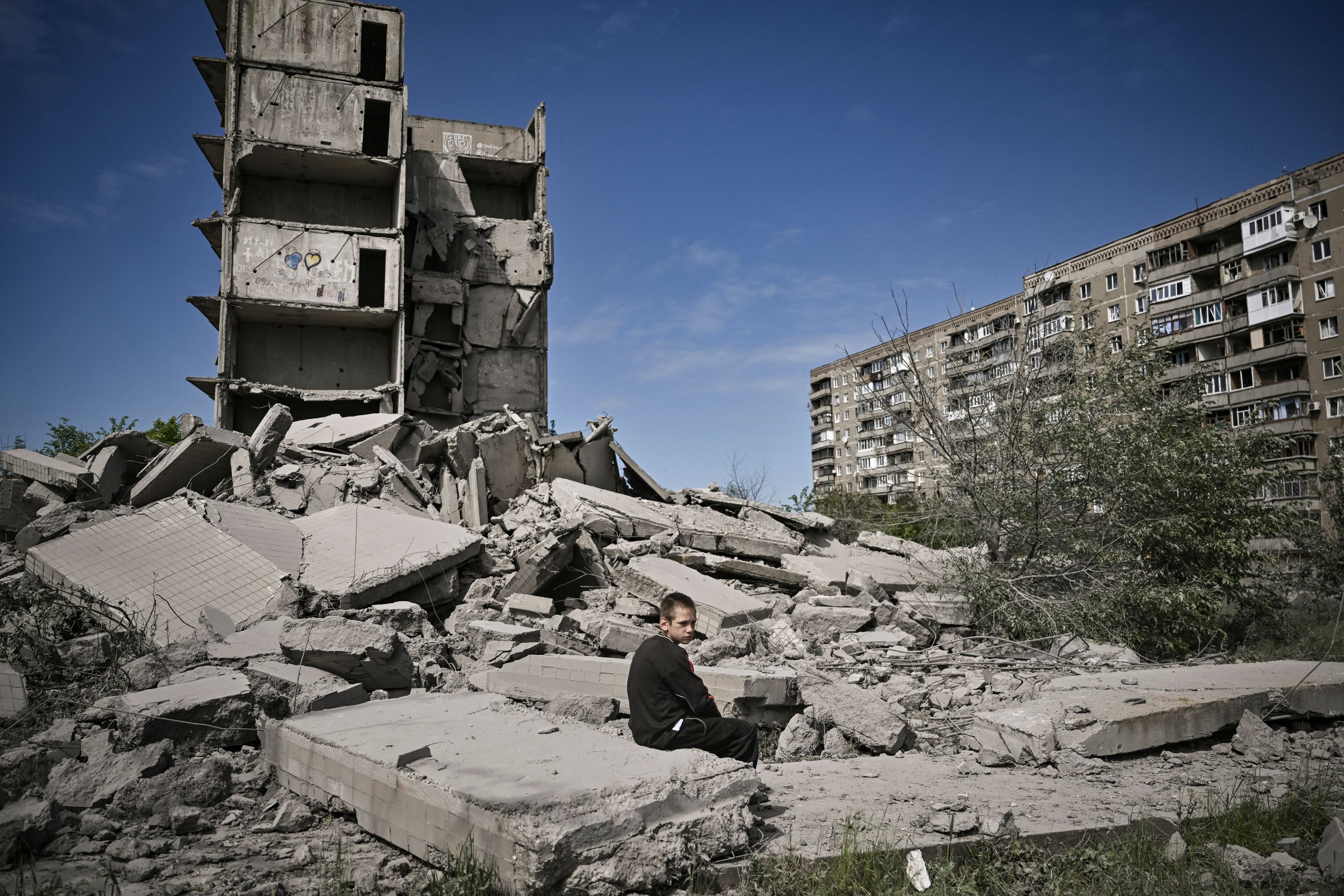 A boy sits amid shelled buildings in Kramatorsk in the eastern Ukrainian region of Donbas