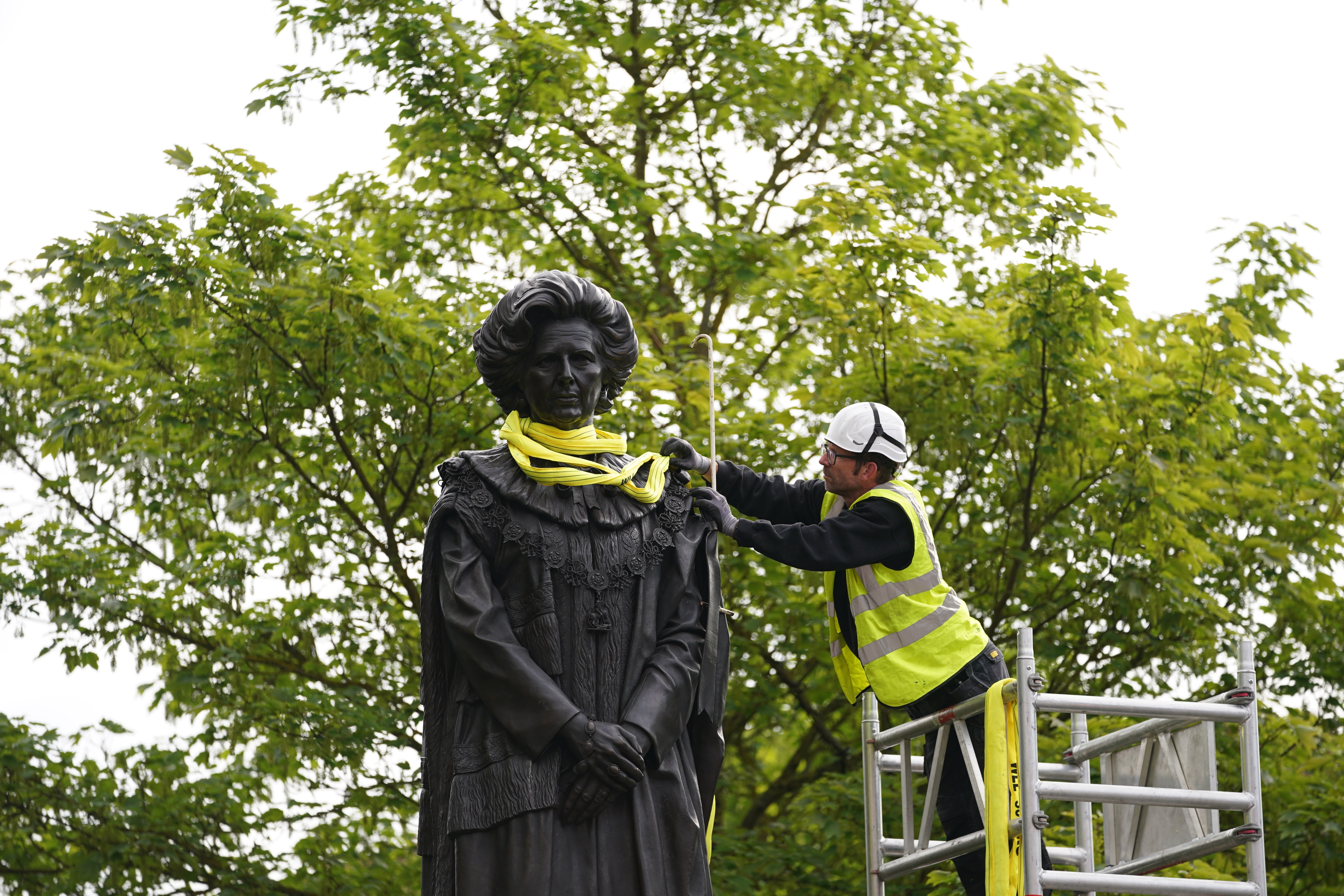 A worker removes the lifting straps from the newly installed statue of Baroness Margaret Thatcher (Joe Giddens/PA)
