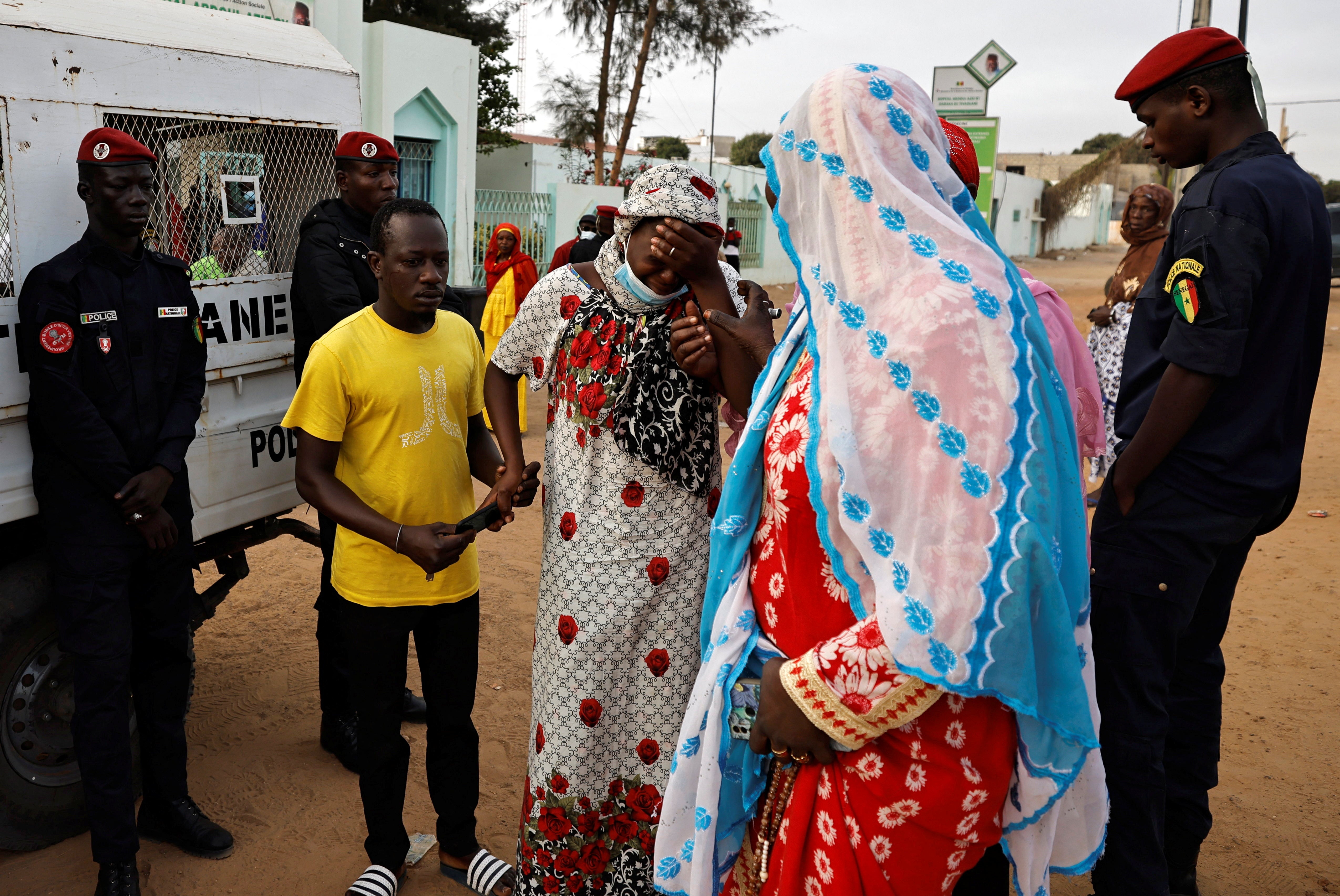 Kaba, a mother of a ten-day-old baby, reacts as she is comforted by relatives