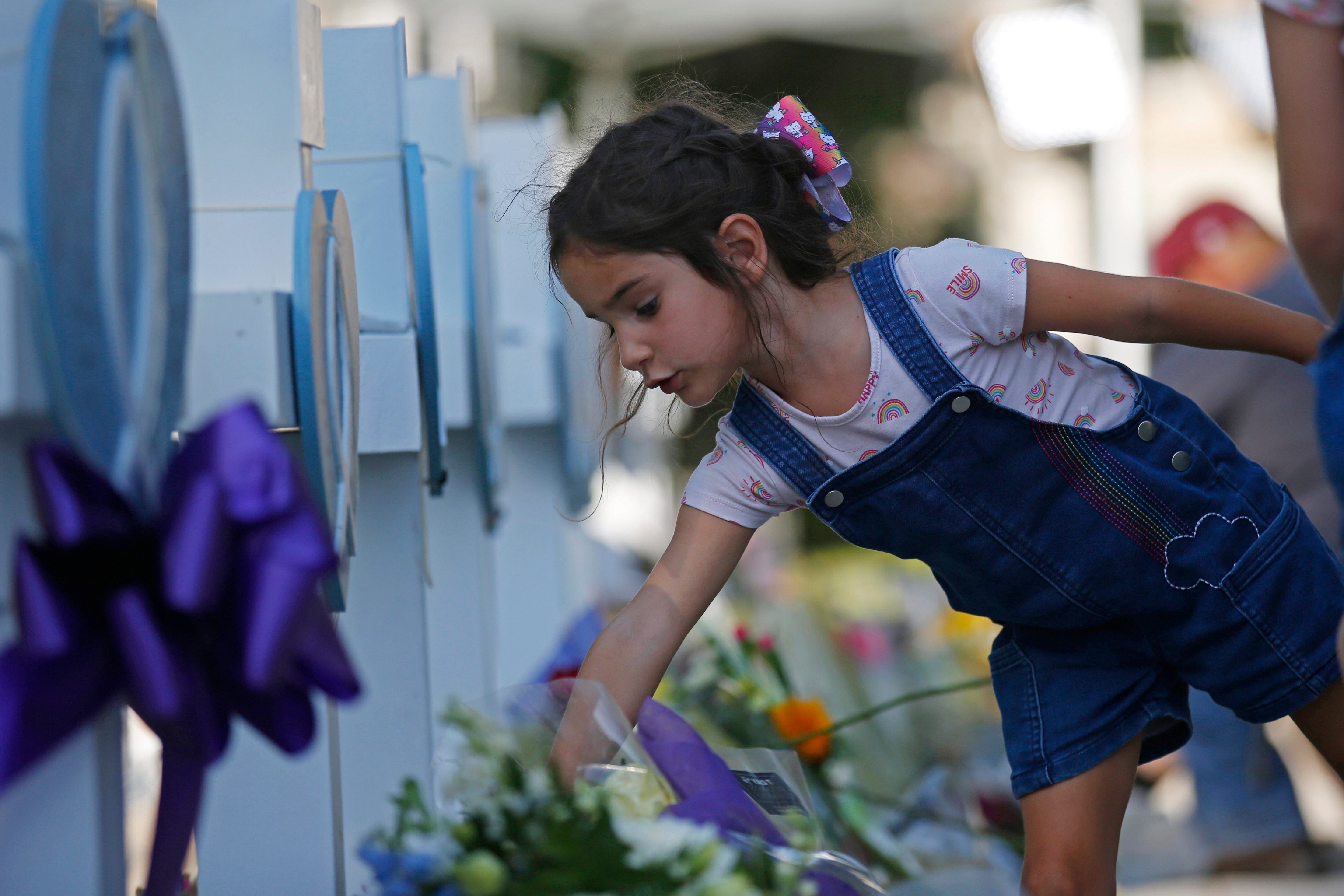 A child leaves flowers at a memorial site for the victims killed in this week's elementary school shooting in Uvalde, Texas