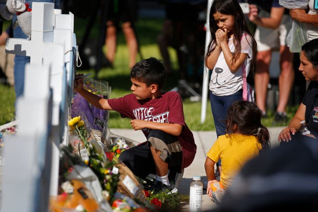 <p>A child writes a message on a cross at a memorial site for the victims killed in this week's elementary school shooting in Uvalde, Texas, Thursday, May 26, 2022. (AP Photo/Dario Lopez-Mills)</p>