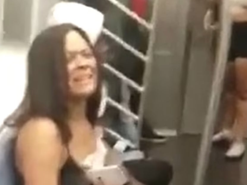 A woman on a New York City subway train pleads for help as the man in the white hoodie next to her grabs her hair after going on an expletive-filled tirade around the cabin.