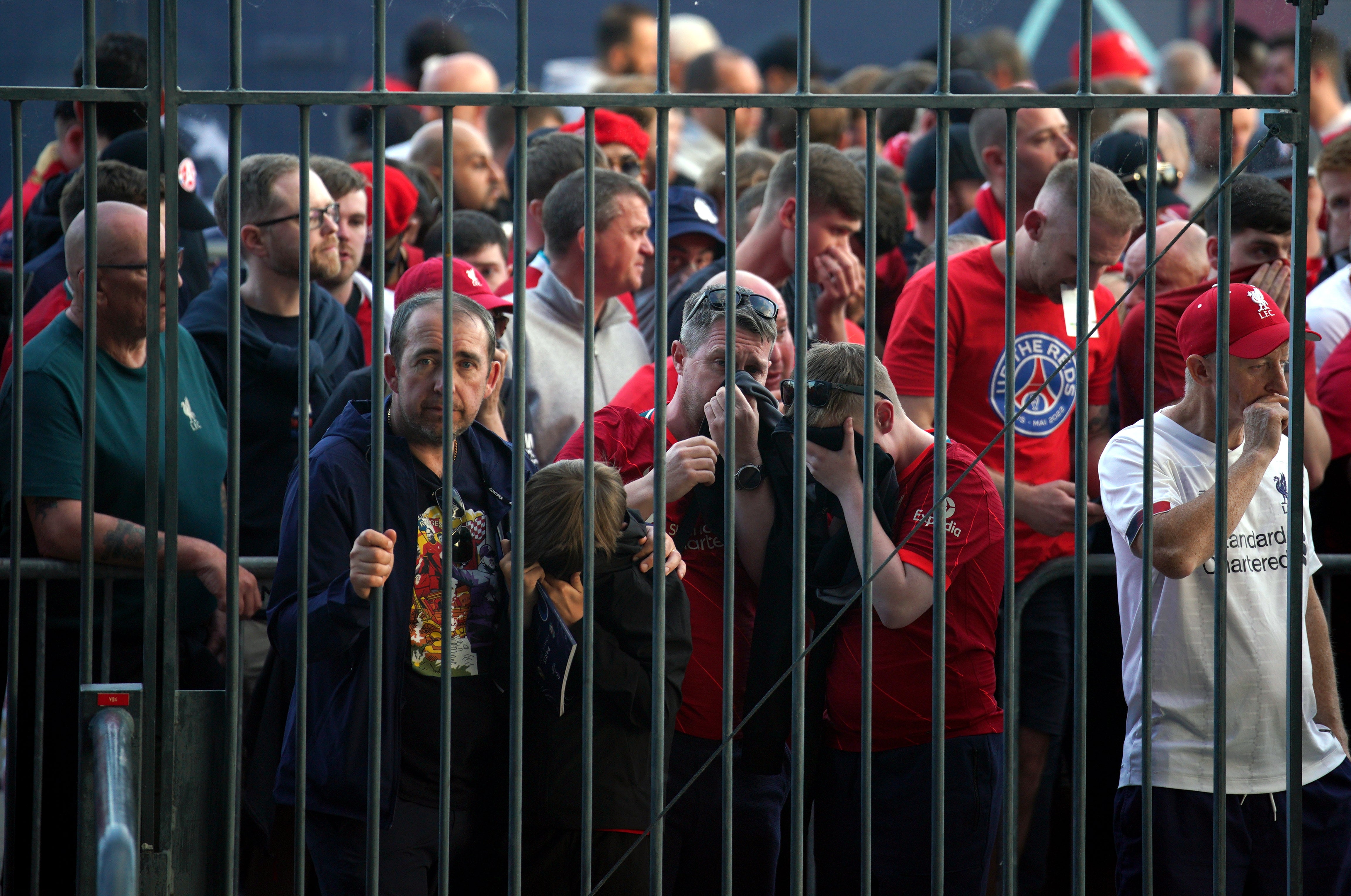 Liverpool fans cover their mouths and noses as they queue to gain entry to the Stade de France (Peter Byrne/PA)
