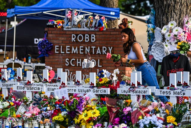 <p>A girl lays flowers at a makeshift memorial at Robb Elementary School in Uvalde, Texas, on 28 May 28 2022</p>