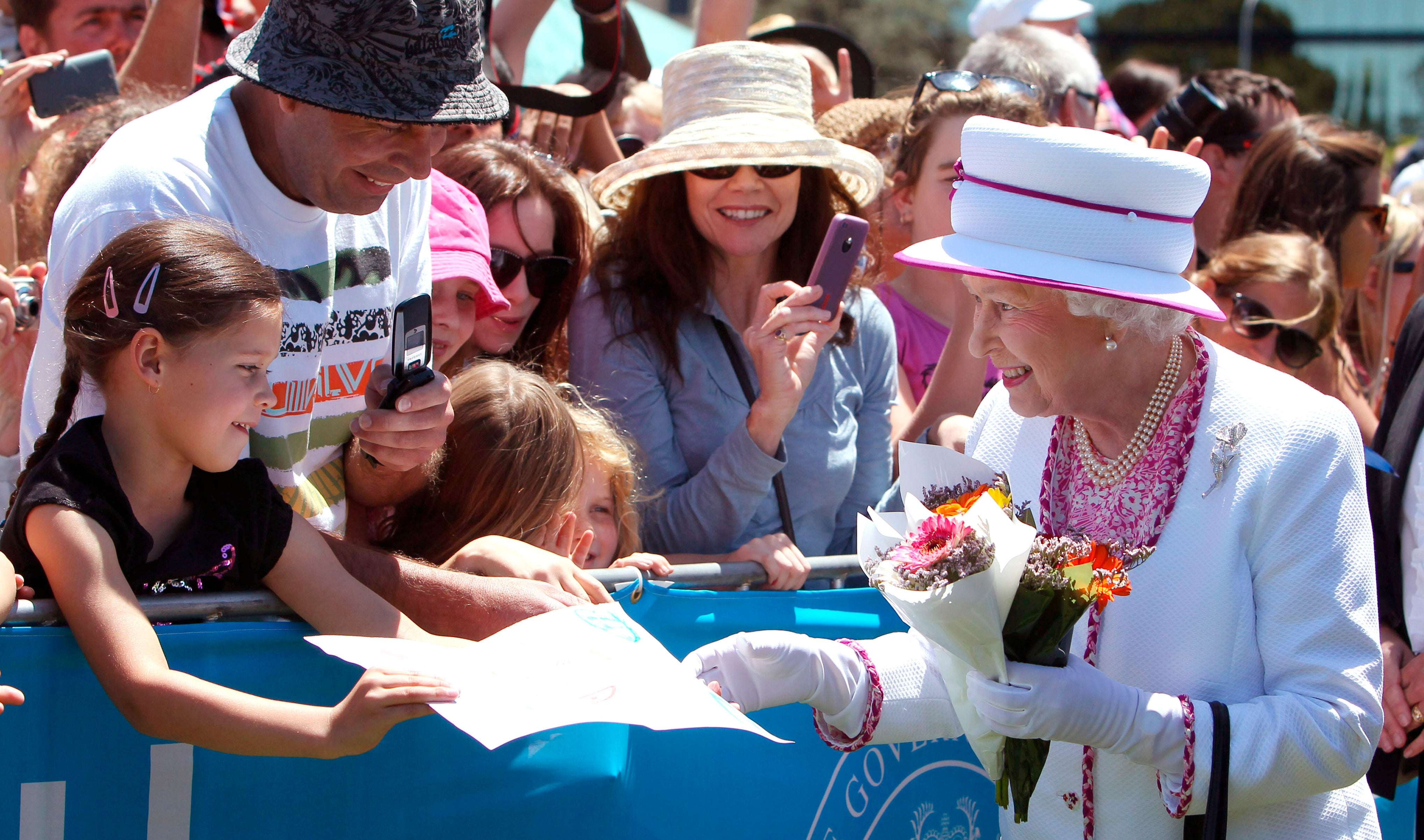 A young girl gives Queen Elizabeth II a picture she walks through the crowd at the Great Aussie Barbecue in Perth, Australia, October 2011.