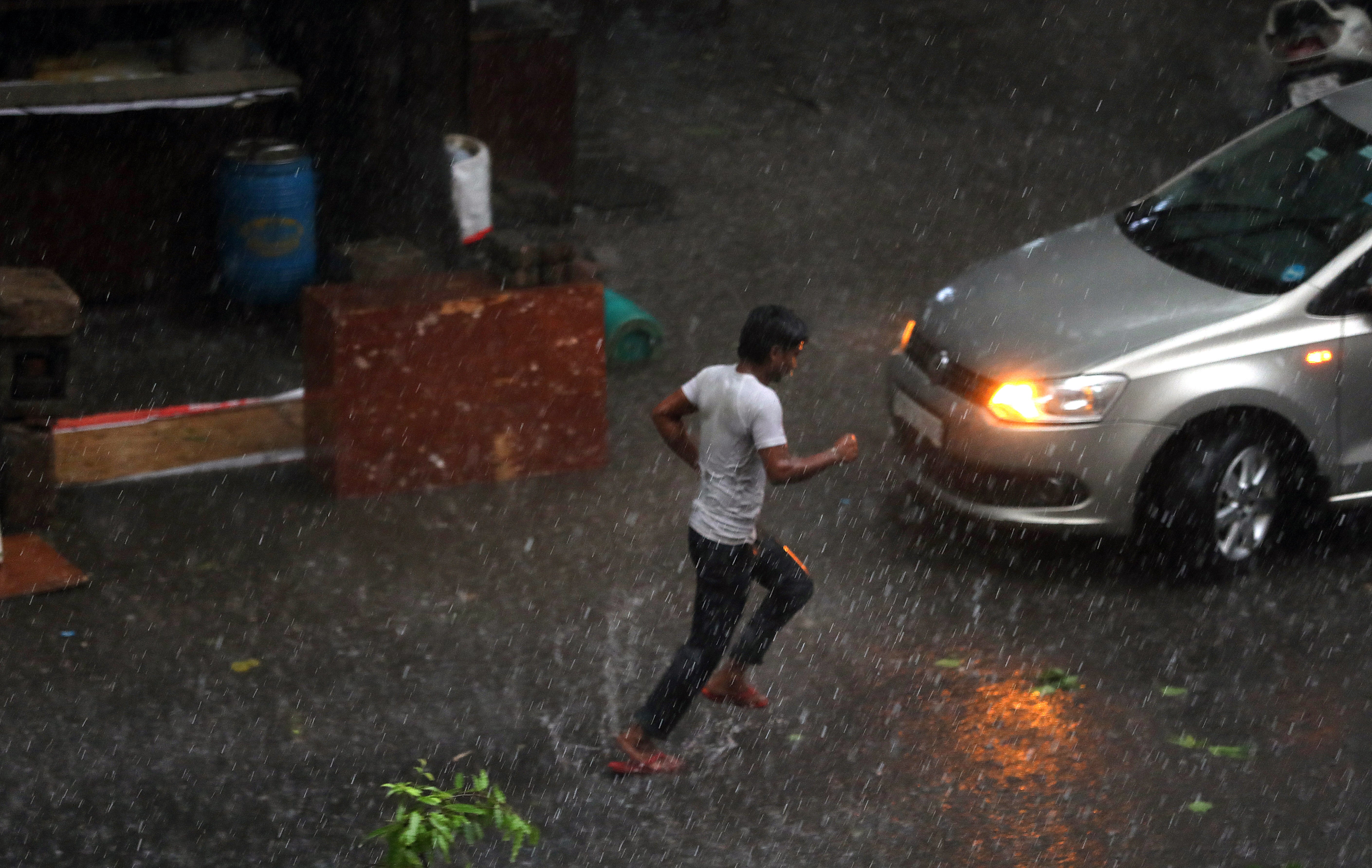 A man runs during sudden strong wind and rain in New Delhi on 30 May that uprooted many trees in and around the Indian capital