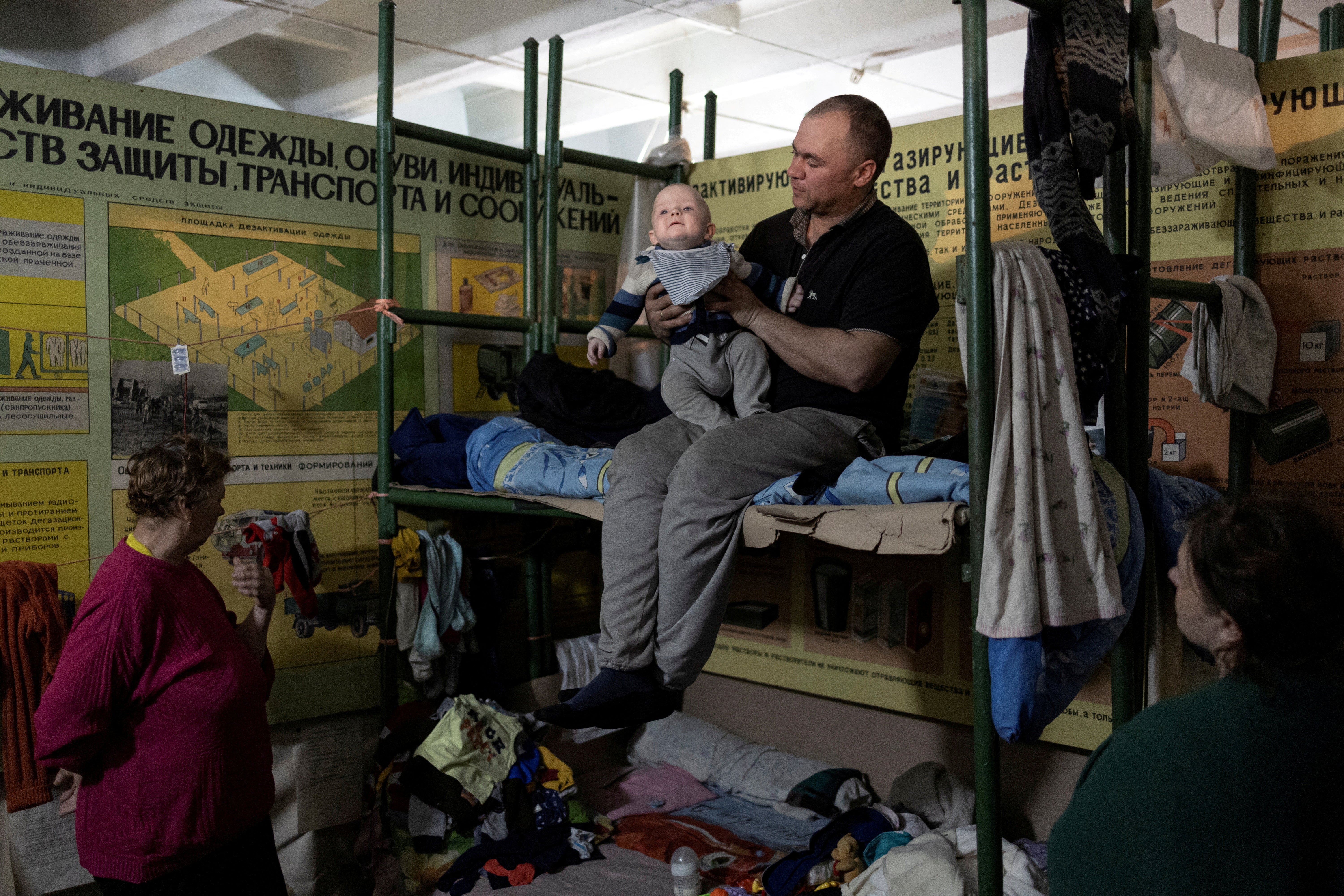 A man holds his baby inside Azot chemical plant's bomb shelter, where people have been hiding from from shelling since the beginning of the war, in Sievierodonetsk, Luhansk region, Ukraine
