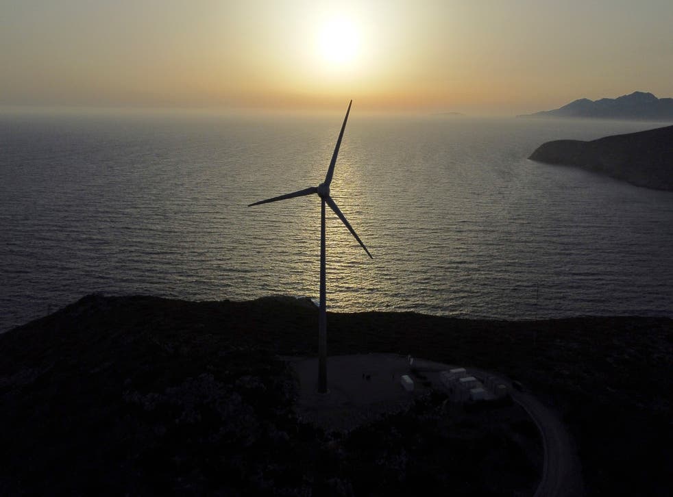 <p>The sun sets behind a wind turbine </p>