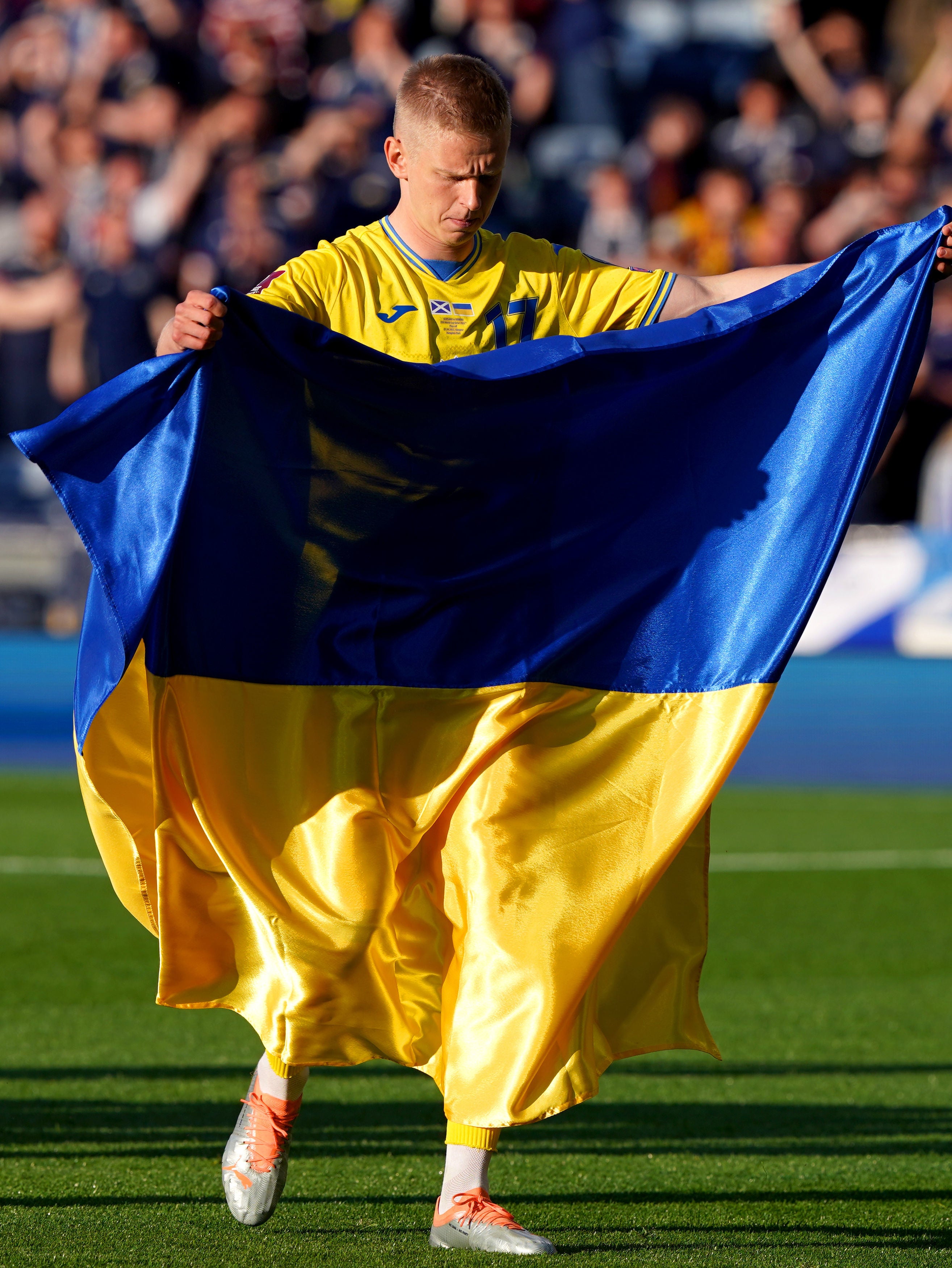 Oleksandr Zinchenko holds up the Ukraine flag on the pitch