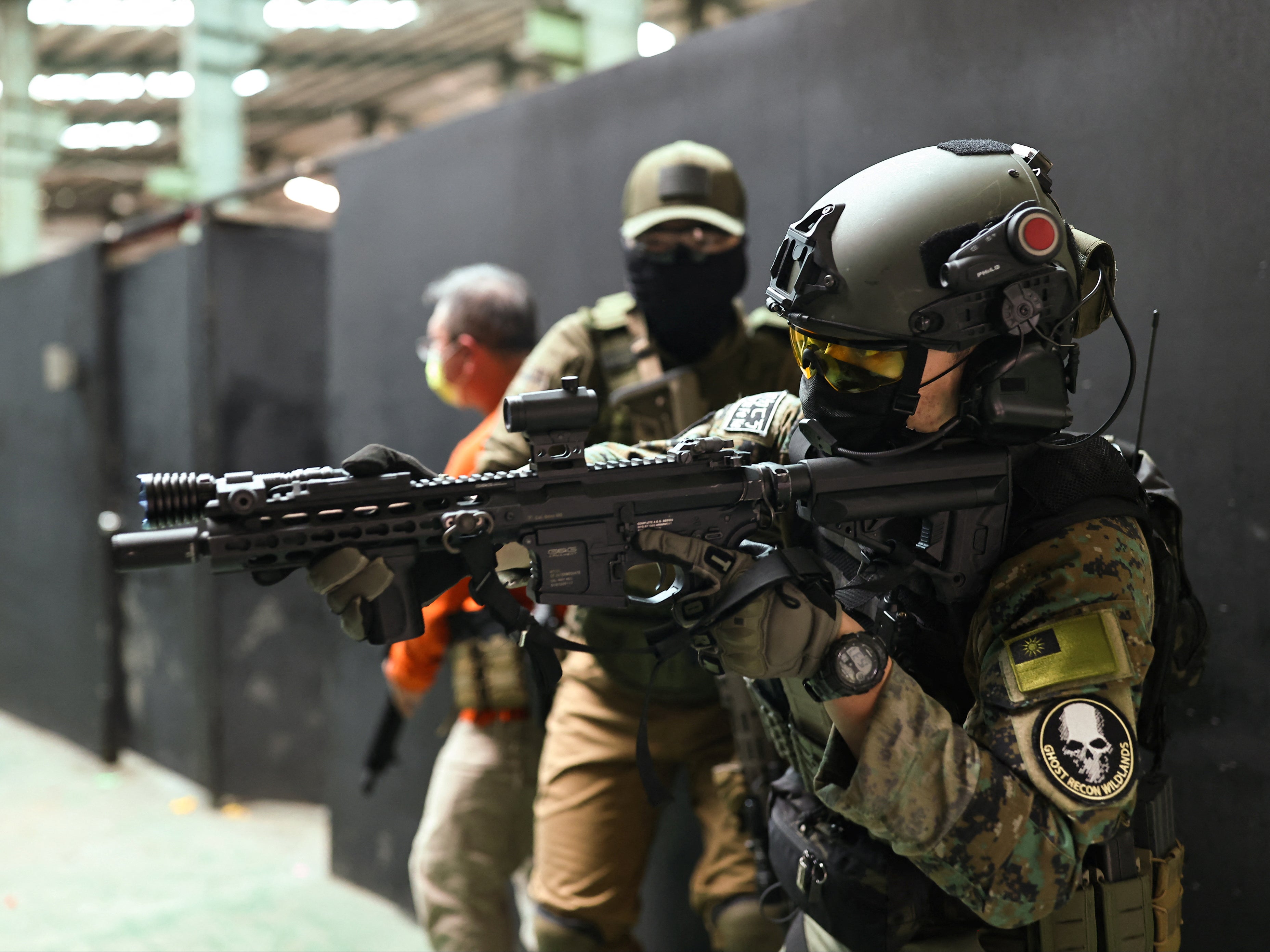 Trainees prepare to enter a building with their airsoft guns during a shooting lesson