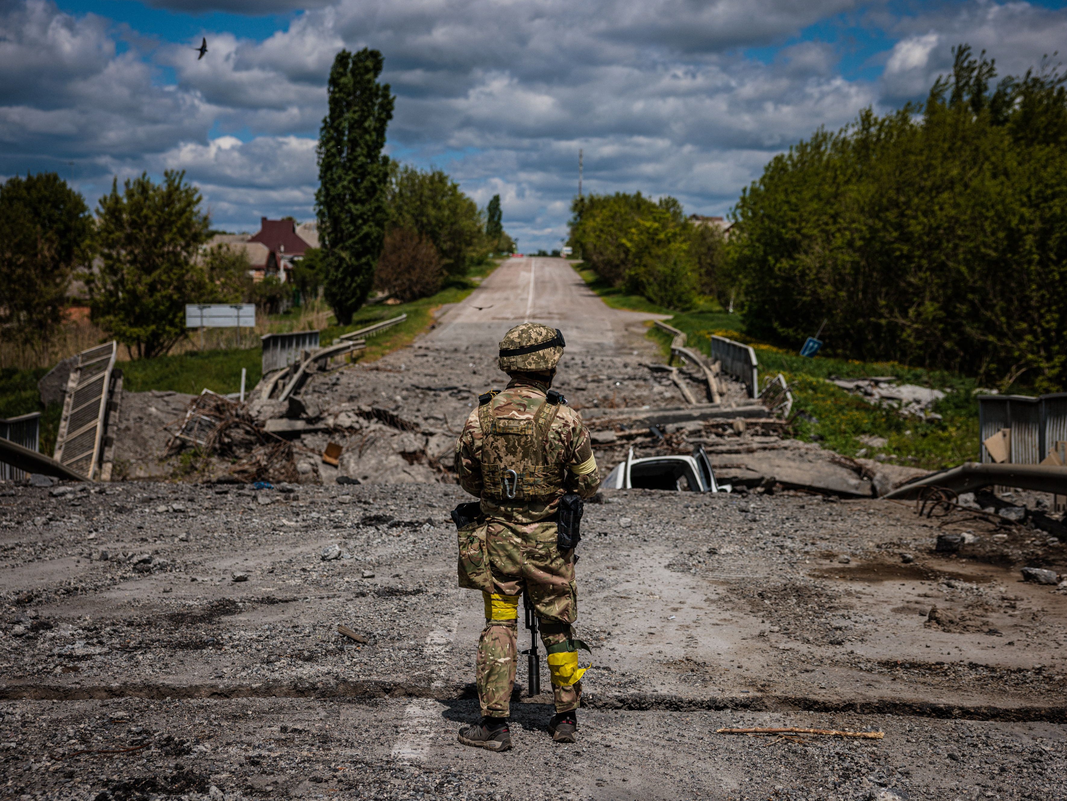 A soldier of the Kraken Ukrainian special forces unit observes a destroyed bridge on the road near the village of Rus'ka Lozova, north of Kharkiv, on 16 May