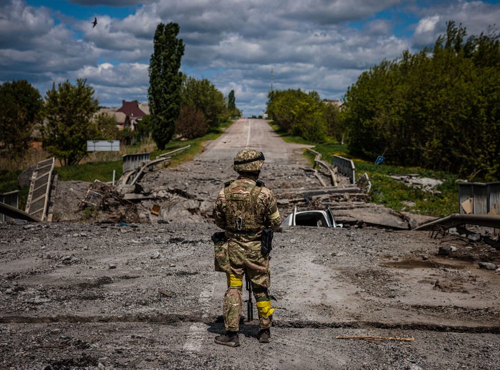 <p>A soldier of the Kraken Ukrainian special forces unit observes a destroyed bridge on the road near the village of Rus'ka Lozova, north of Kharkiv, on 16 May </p>