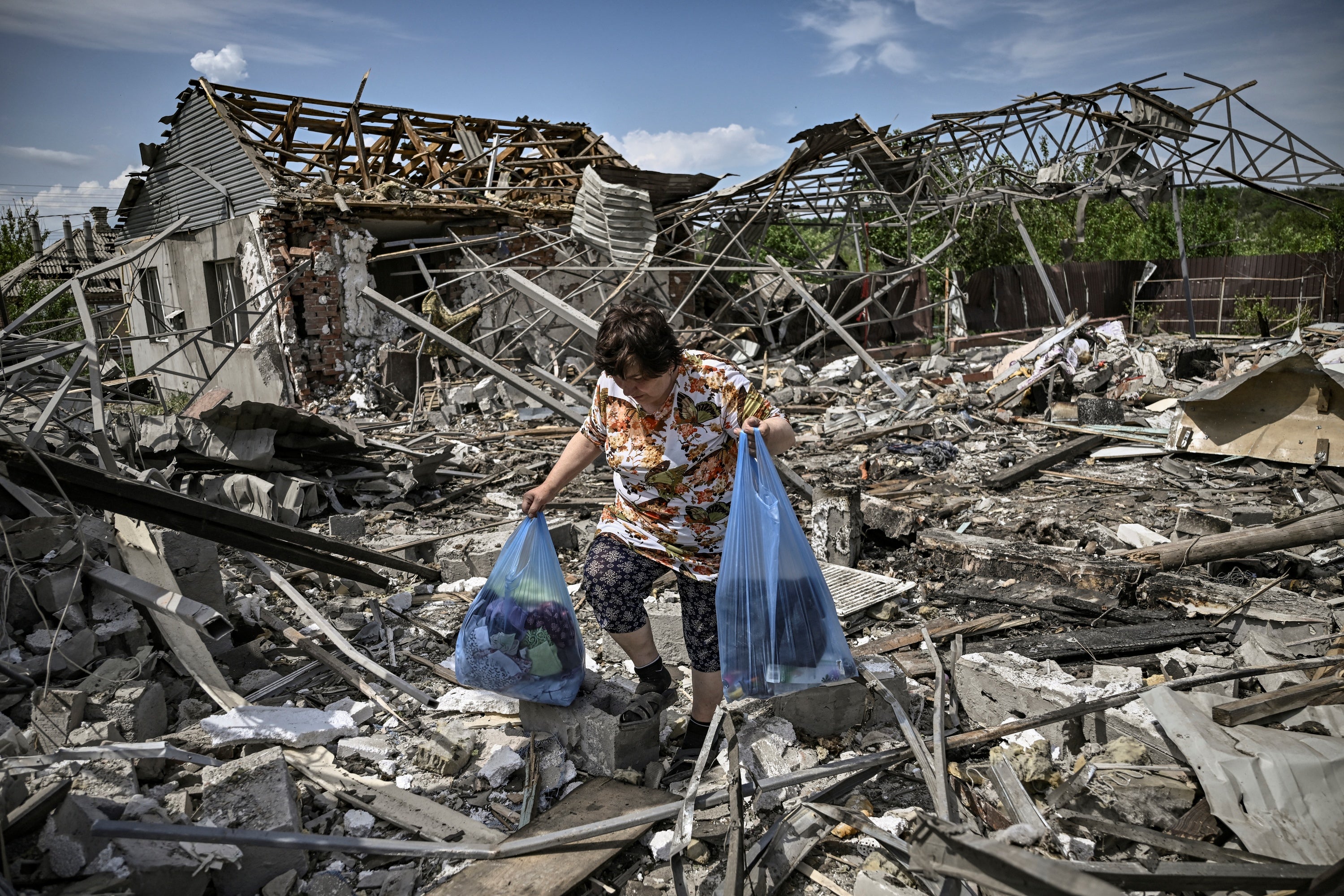 A woman collects belongings in the rubble of her house after a strike destroyed three houses in the city of Slovyansk, in the eastern Ukrainian region of Donbas, on 1 June 2022