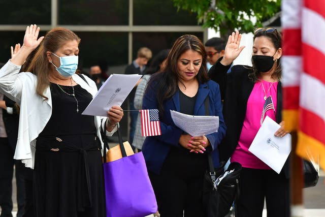 <p>People hold US flags and gesture while attending their Naturalization Oath ceremony for US citizenship in Los Angeles, California, on May 25, 2022</p>