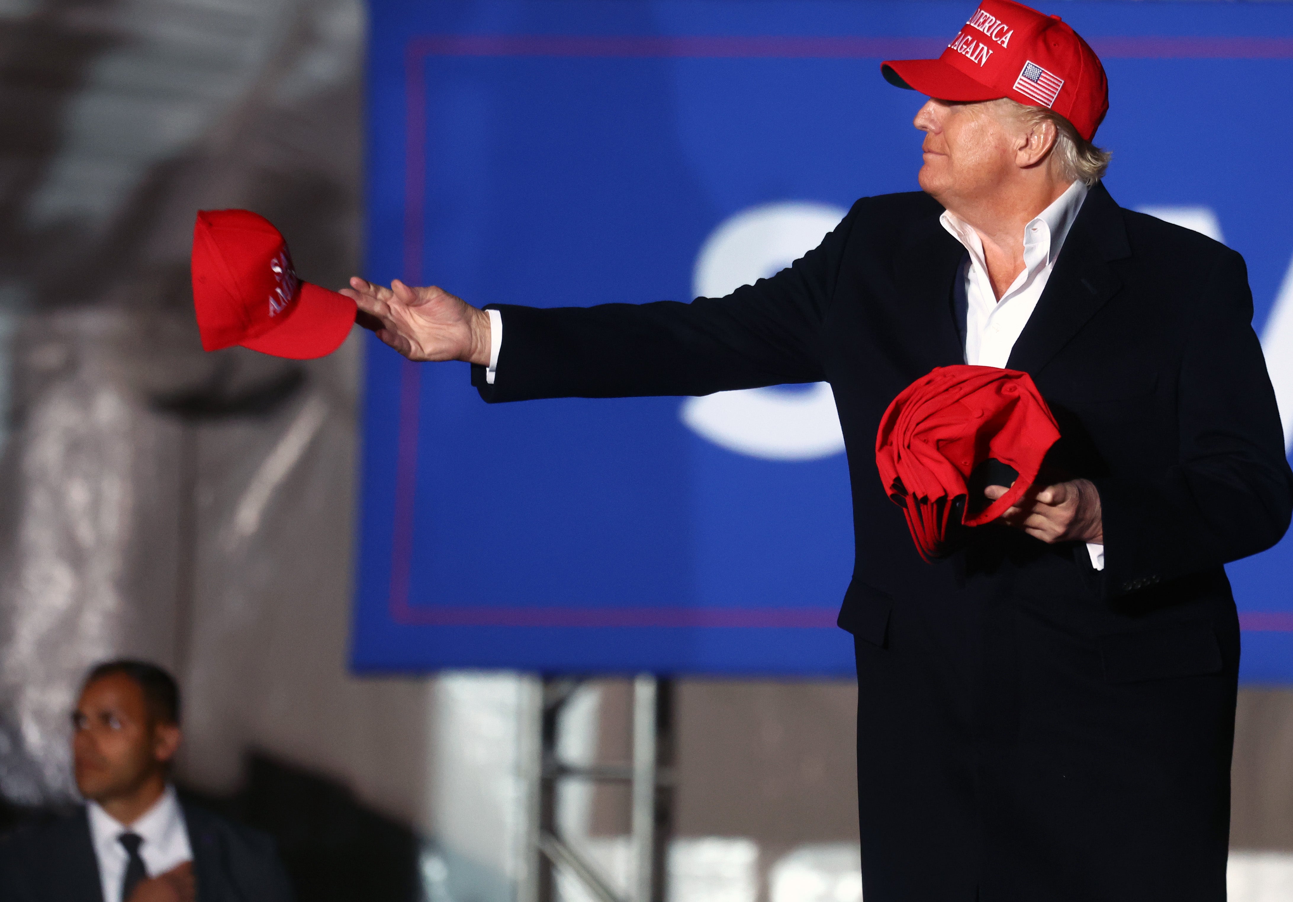 Trump, pictured in 2022, hands out red MAGA hats - a common gift he offers his supporters at rallies or smaller events