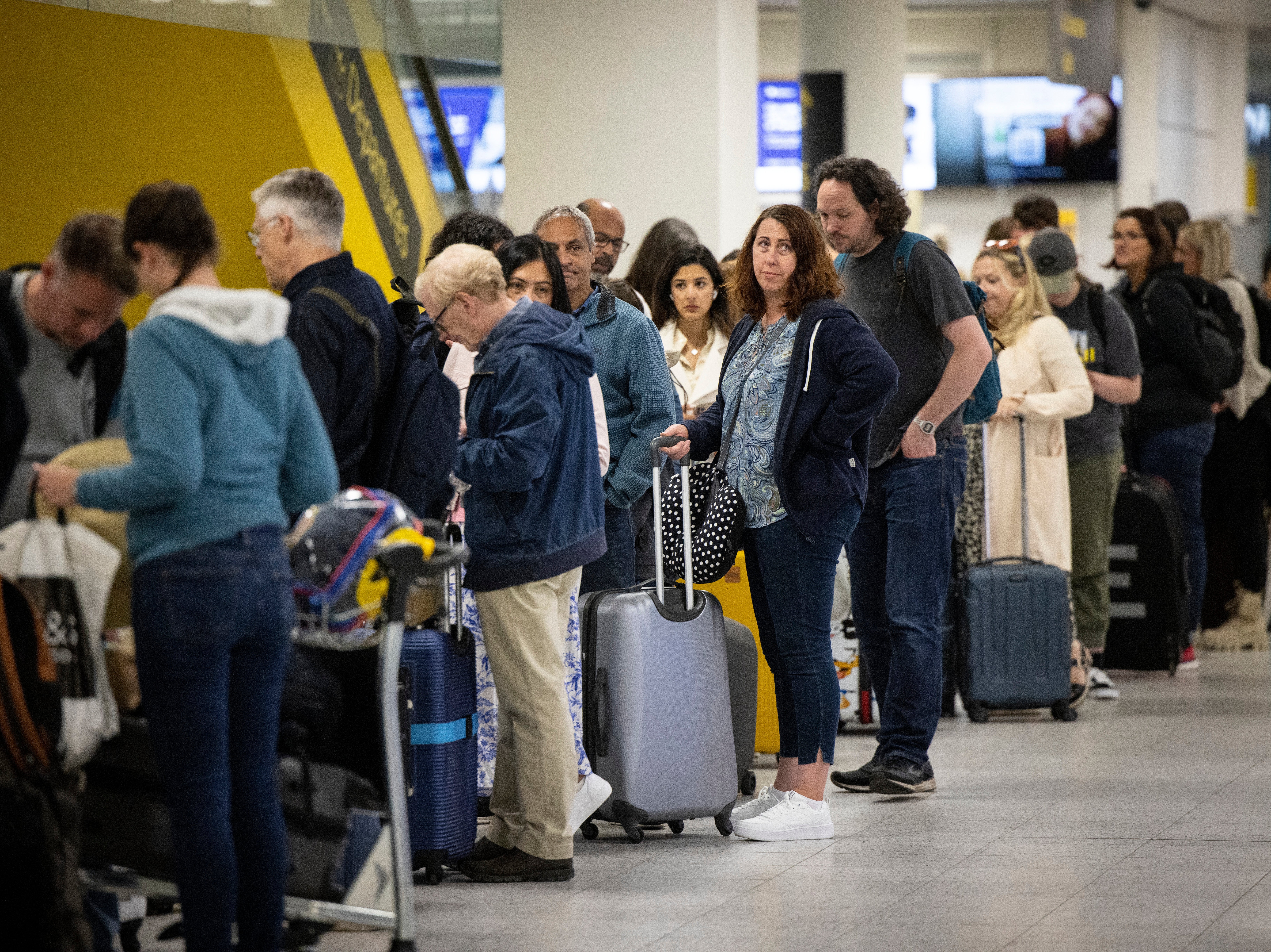 Travellers queue to check in for their flights at Gatwick Airport