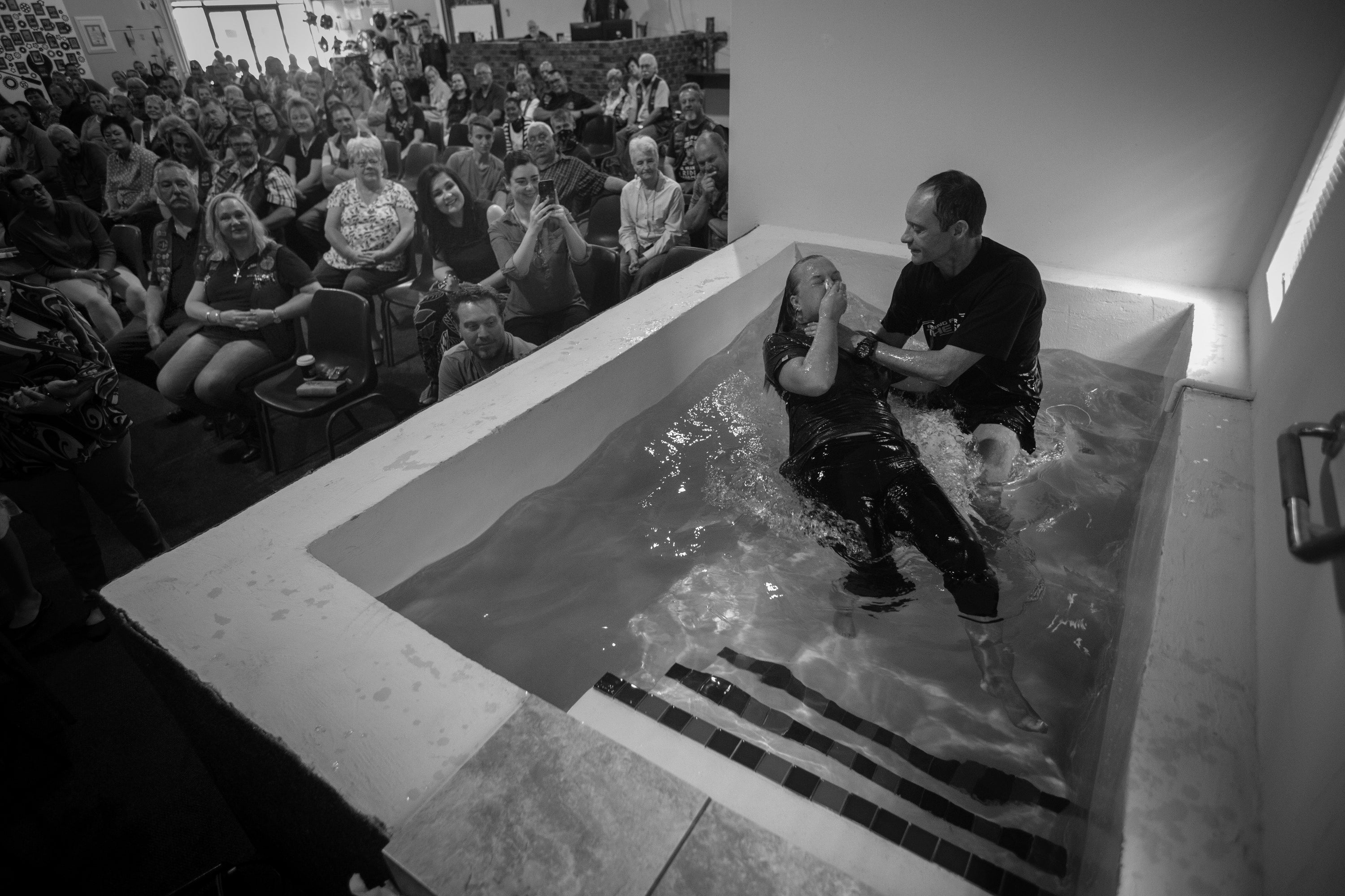 Pastor Mozzy Delpeche guides a rider into a bath as he baptises her during a weekly service at the CMA Midvaal chapter in Vereeniging