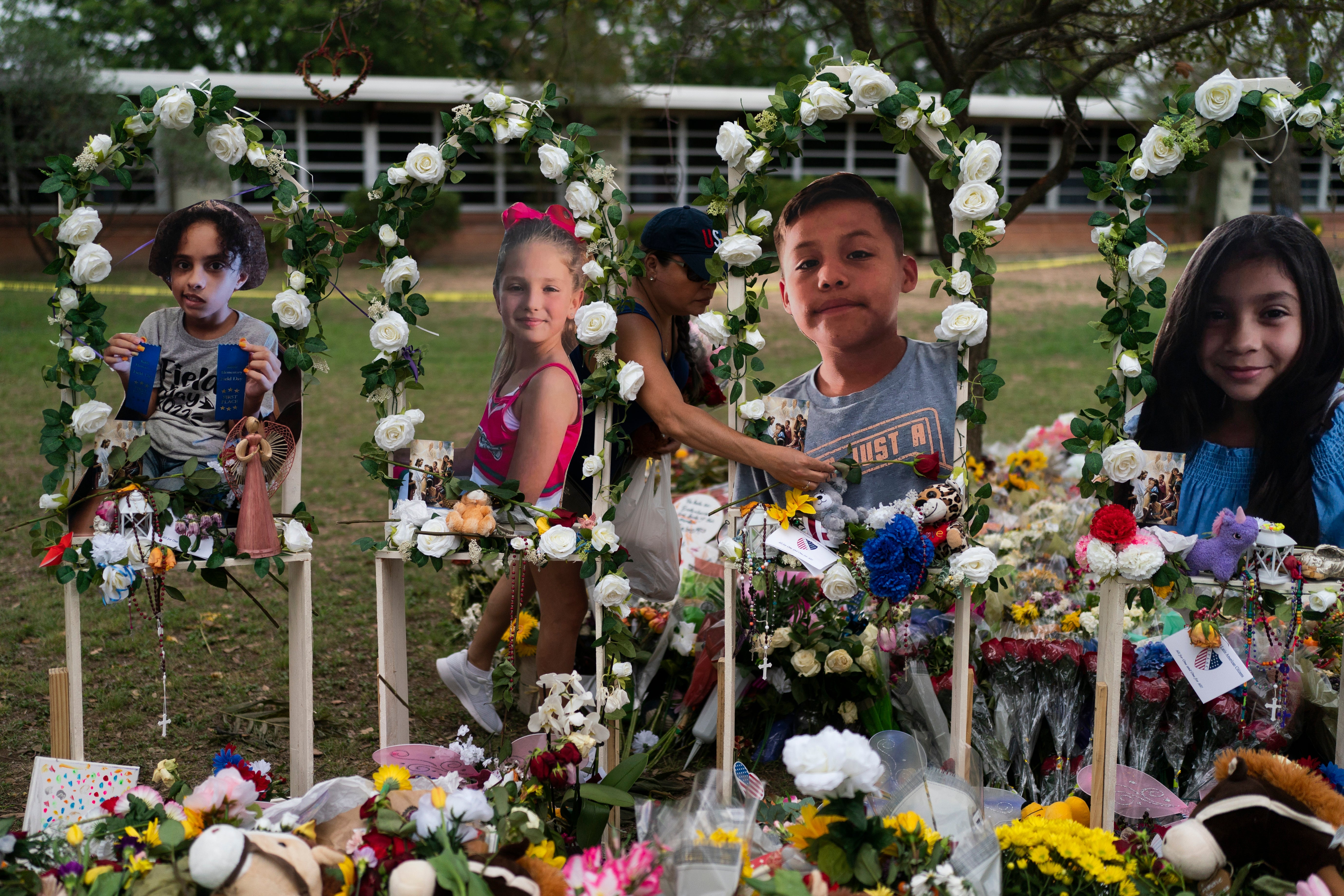 Cat Perez, 39, lays flowers at a memorial at Robb Elementary School in Uvalde, Texas Monday, May 30, 2022, to honor the victims killed in last week's school shooting. Photographs of the victims, from left, show Layla Salazar, McKenna