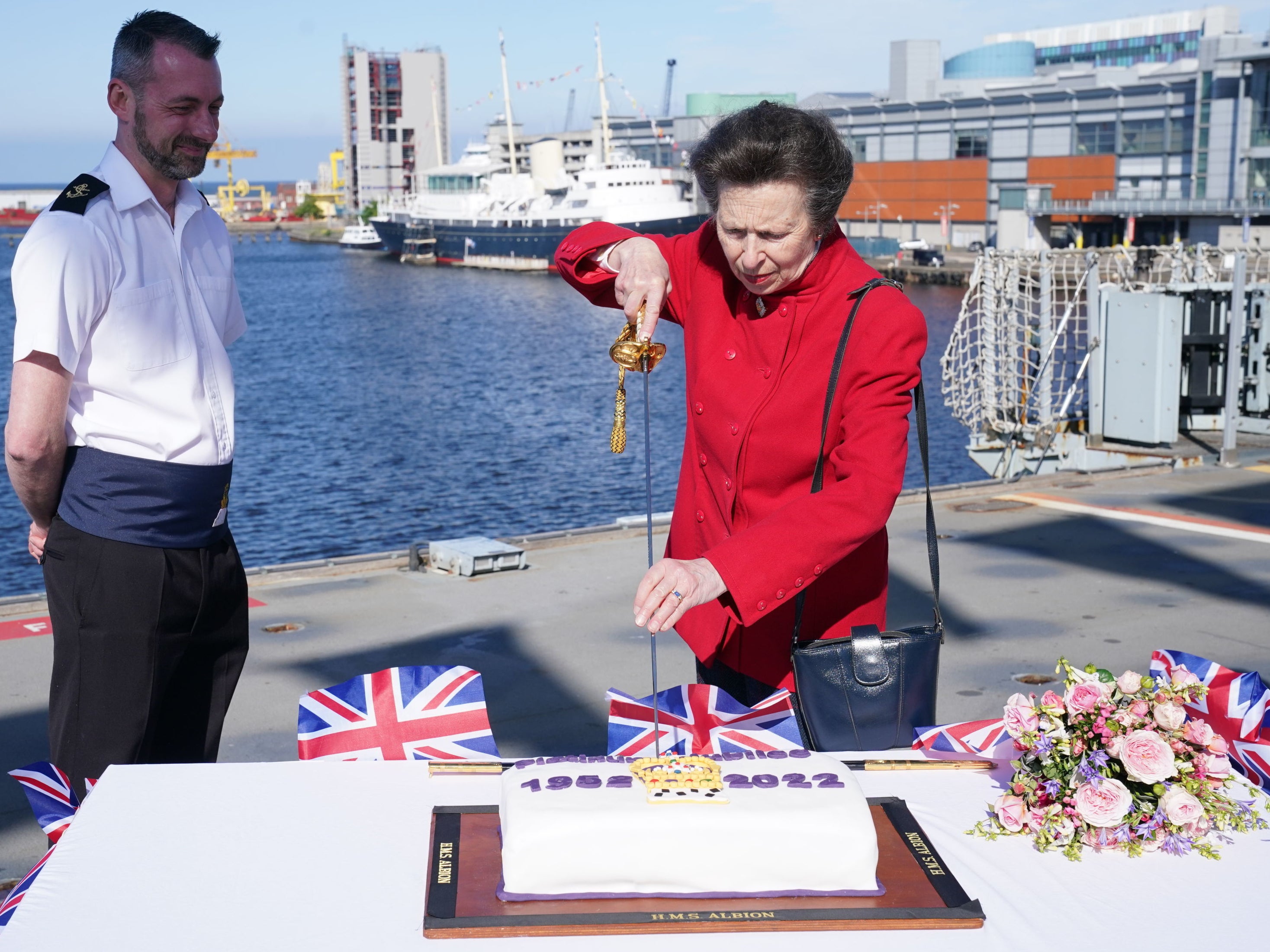 The Princess Royal uses the Captain's Sword by to cut a commemorative Jubilee cake during her visit to HMS Albion