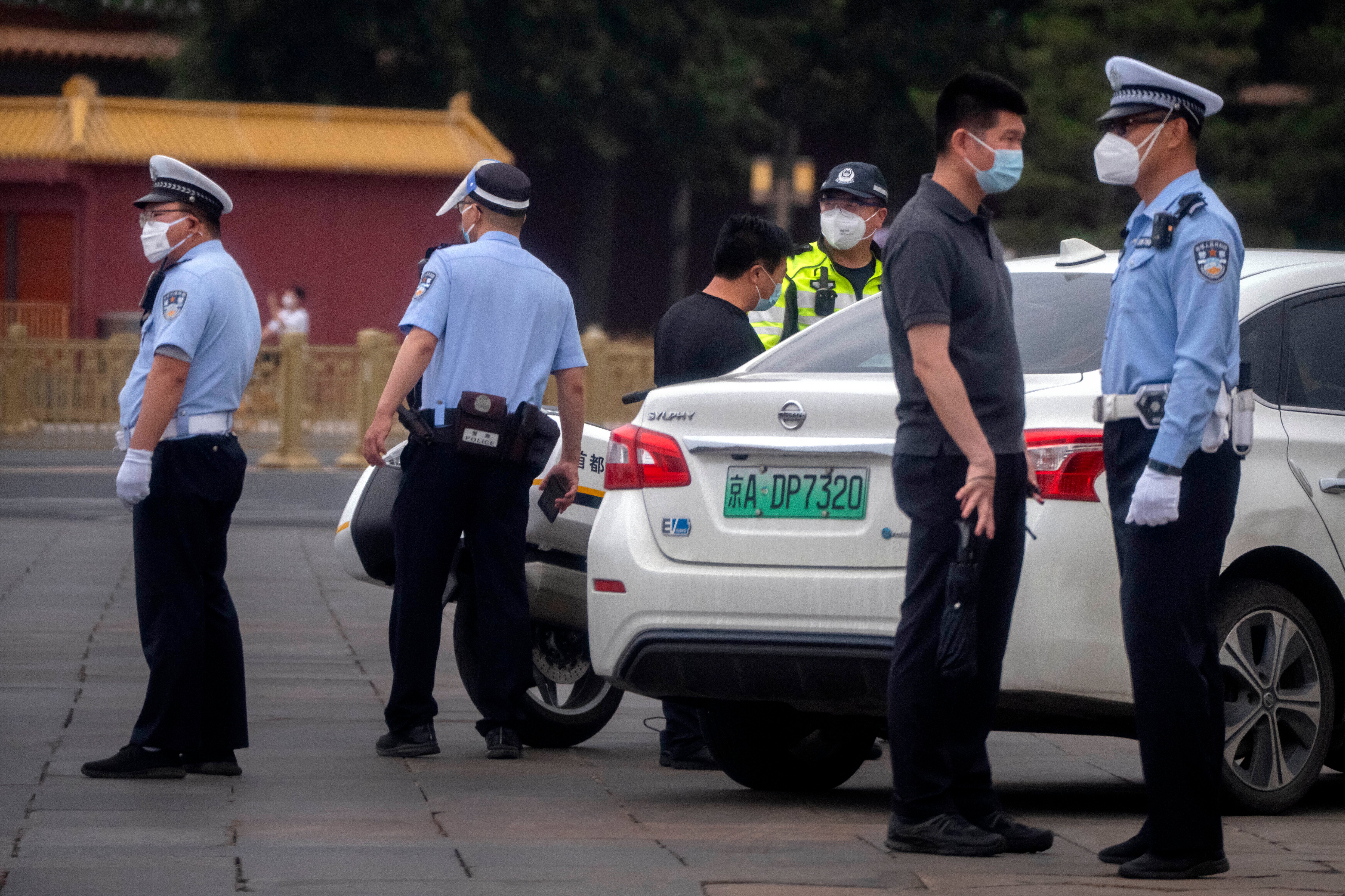 Police officers talk to a man in a street close to Tiananmen Square in Beijing